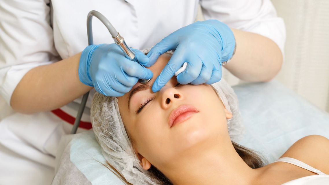 Cosmetologist performing eyebrow microblading on a client.