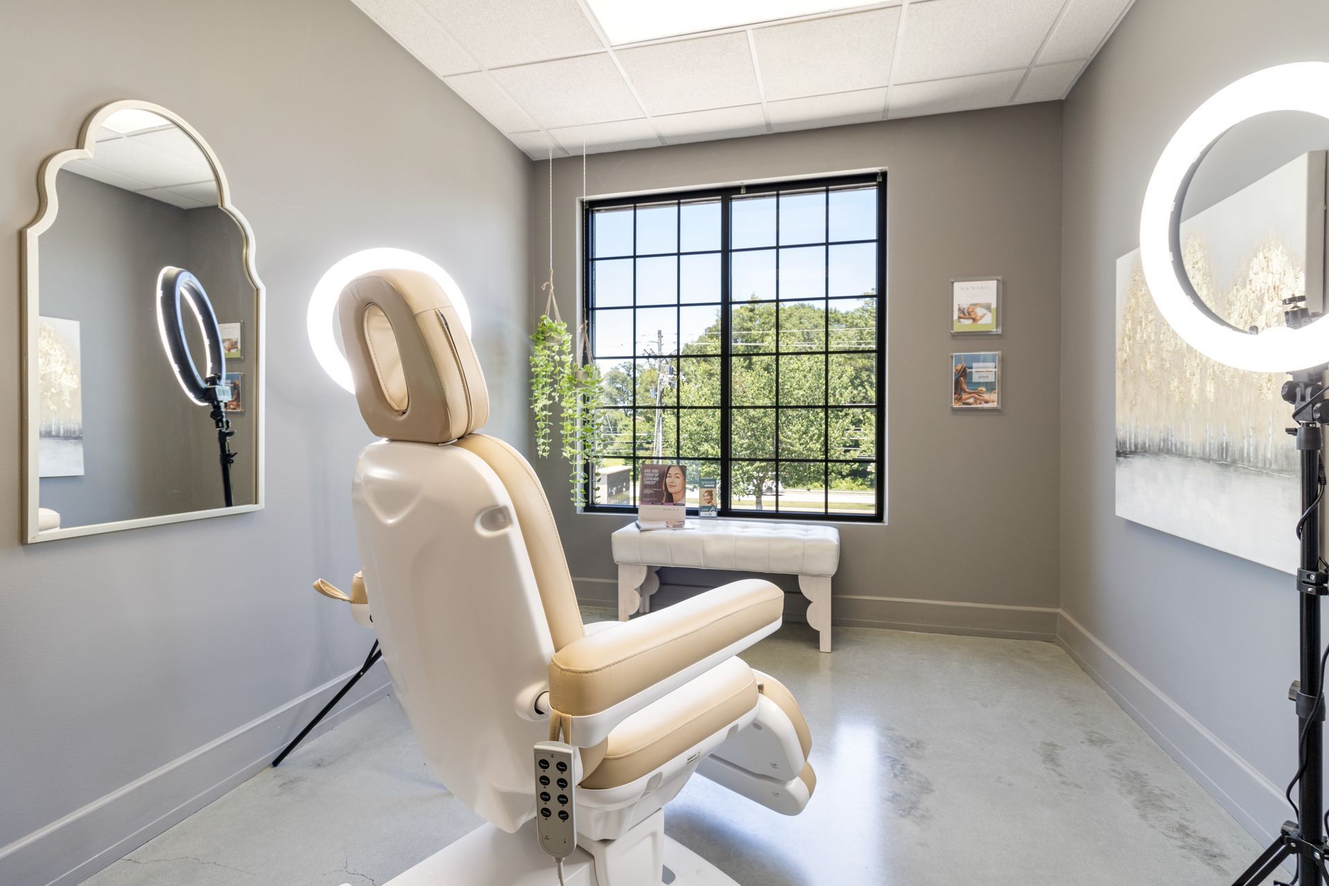 A room with a chair , mirror , and ring lights.