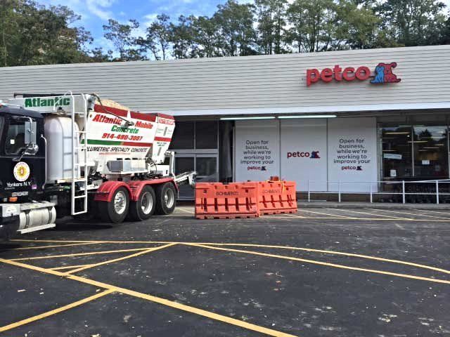 Truck unloading supplies outside Petco storefront with orange barriers in front
