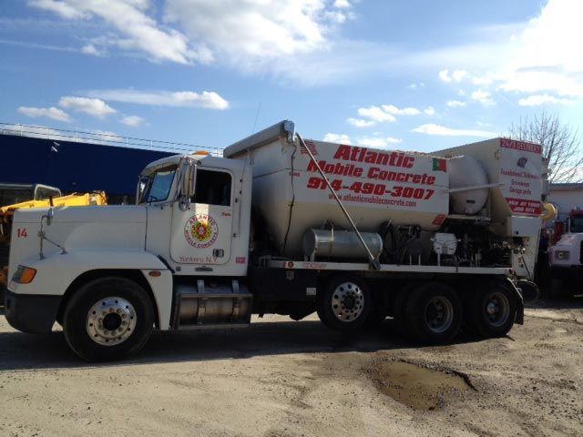 White Atlantic Mobile Concrete truck parked on a road under a blue sky with clouds