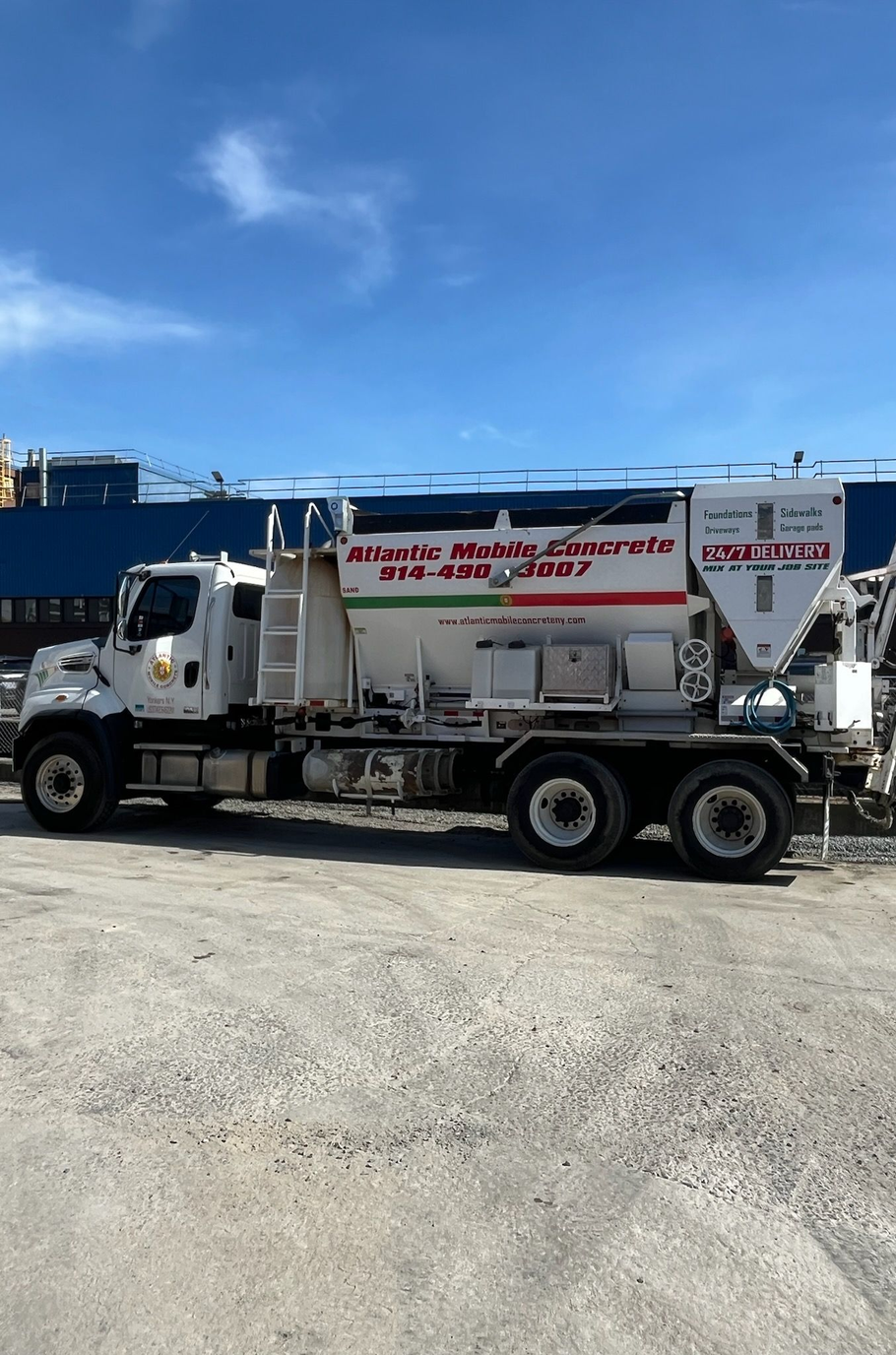 White utility truck with ladder and tank on a gravel lot under a clear blue sky