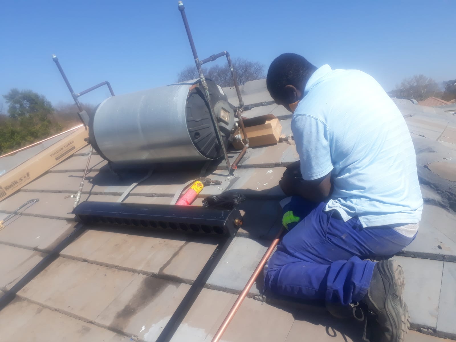 Plumber on a roof installing a new solar geyser