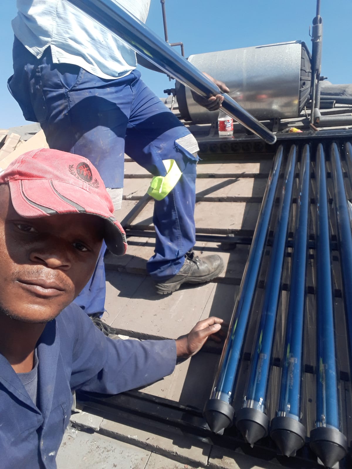Two plumbers on a roof installing a new solar geyser