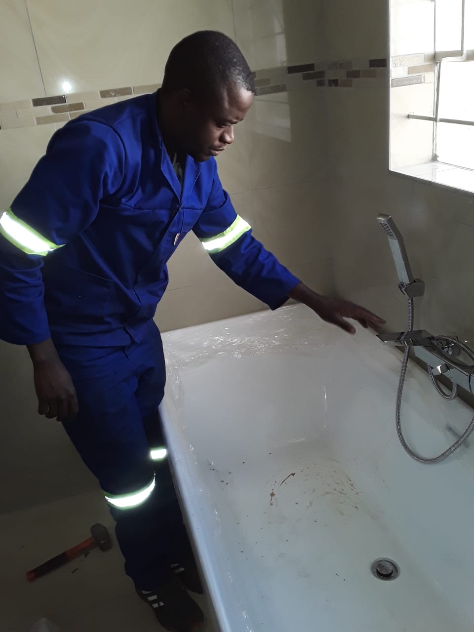 plumber standing over new bath installation holding the tap