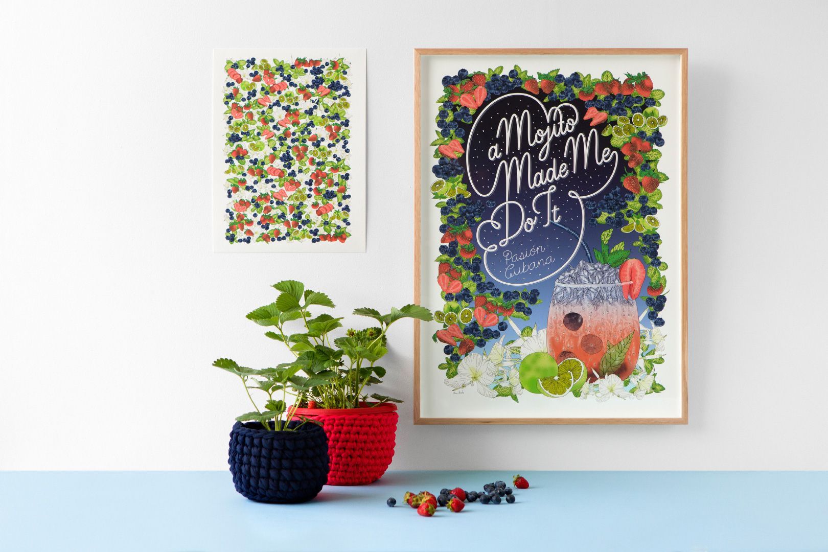 Two framed floral artworks featuring a Mojito cocktail above small potted plants on a pale blue shelf