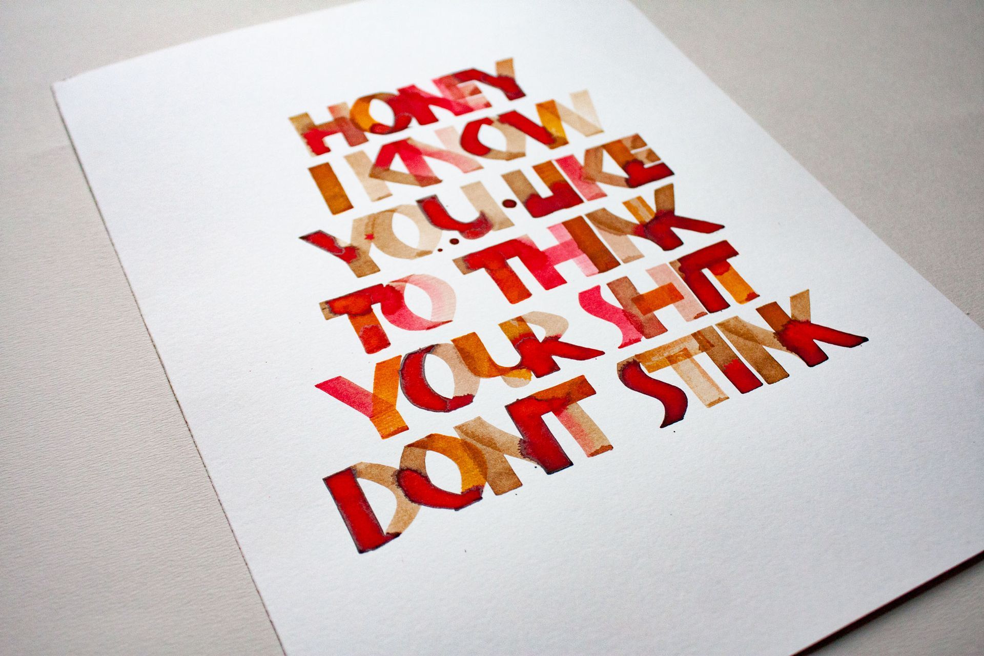 A print on white paper with red and orange layered block lettering that reads: 