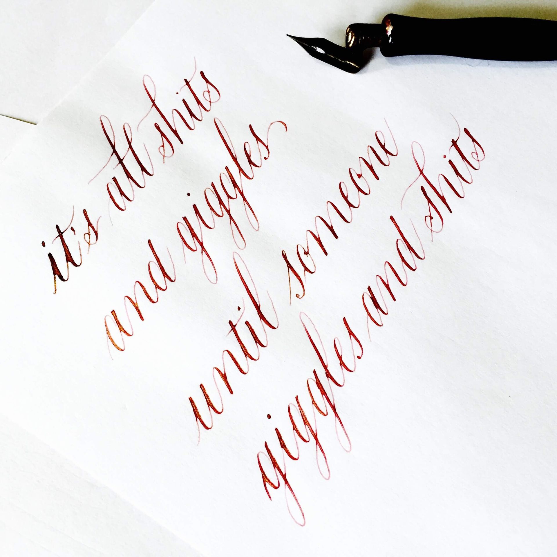 A calligraphy pen rests on paper with the handwritten text,