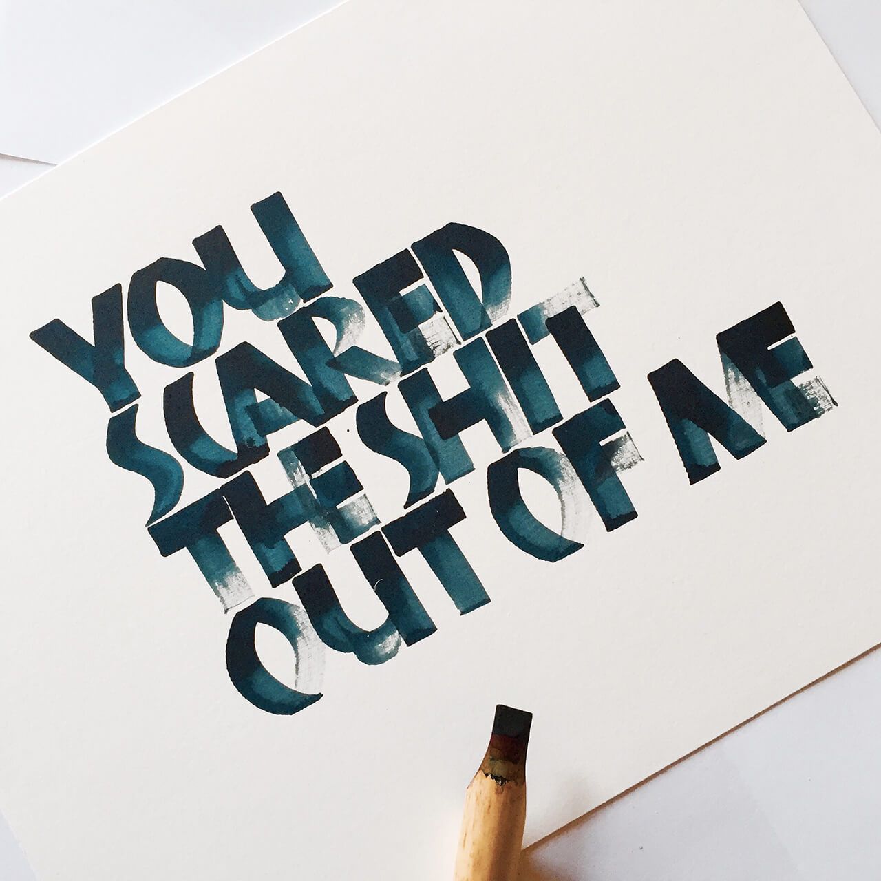 Dark blue hand-lettered text on white paper reads: