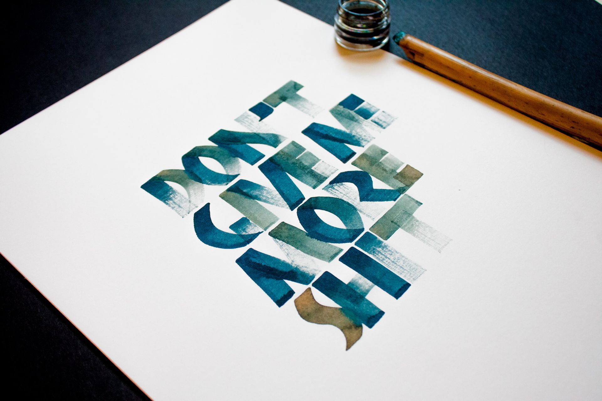 Calligraphy in teal and grey brush strokes on white paper reads