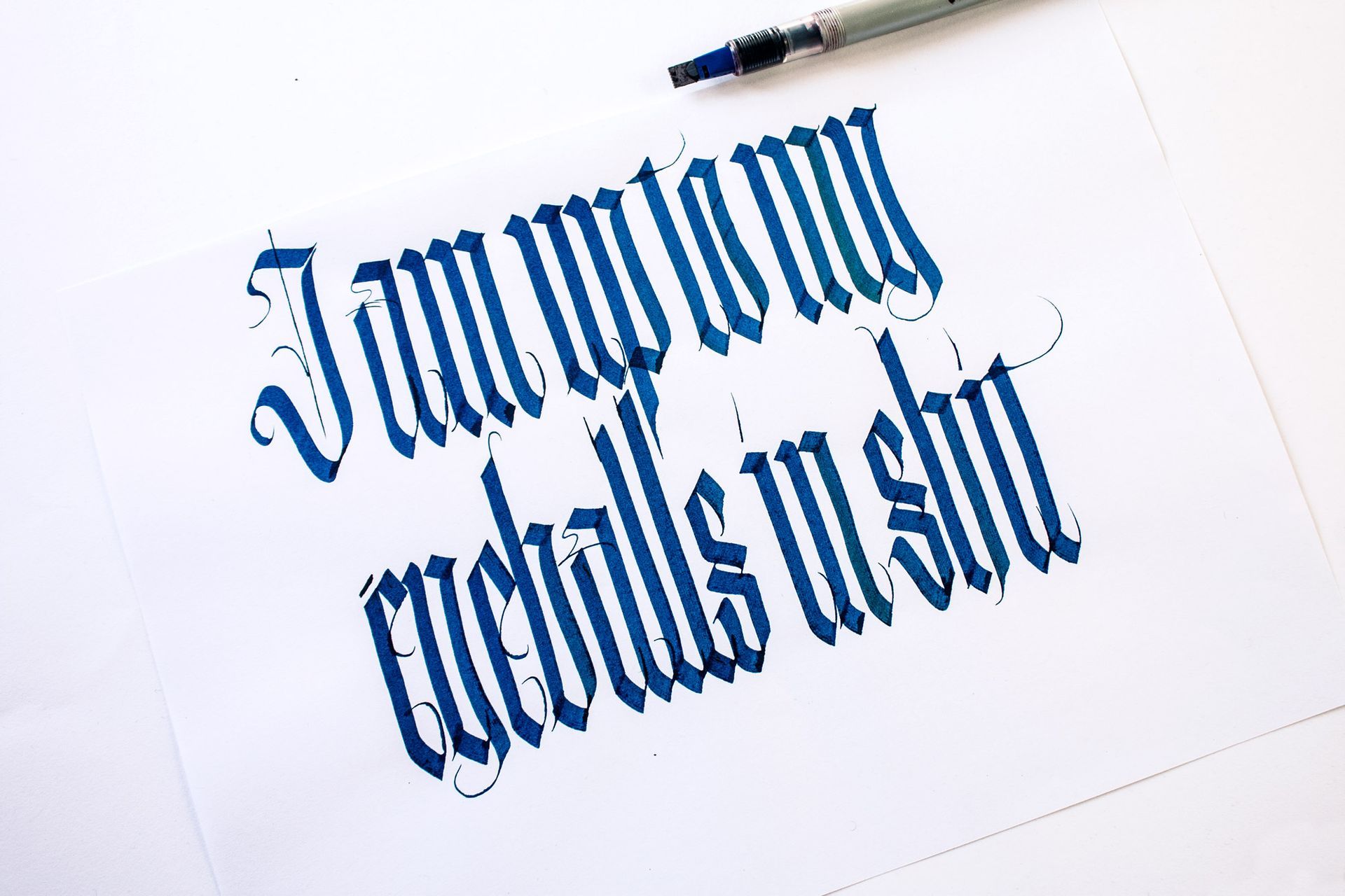 Blue calligraphy written in Gothic style on white paper, reading