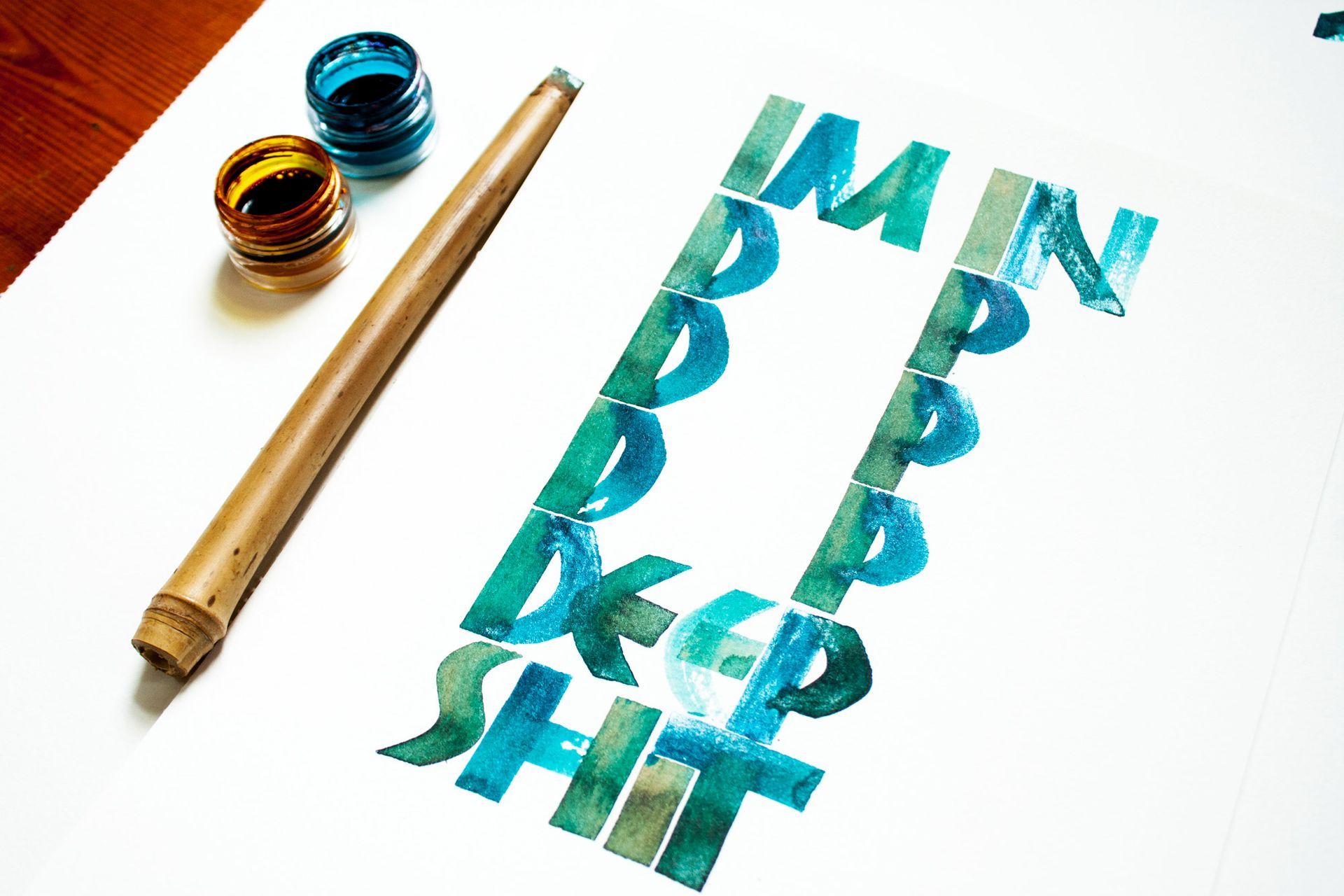 Calligraphy written in teal ink on paper, spelling