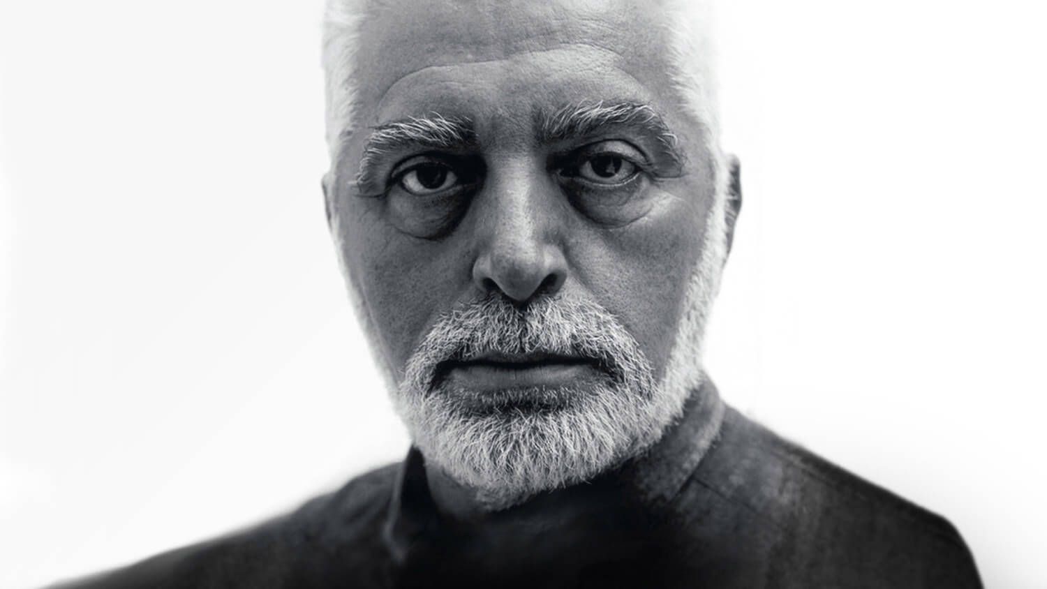 Black-and-white portrait of a serious Paco Rabanne with a white beard against a plain background