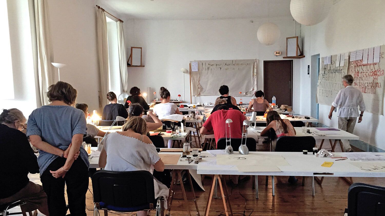 People seated around tables in a bright workshop room, facing a presentation at the front.