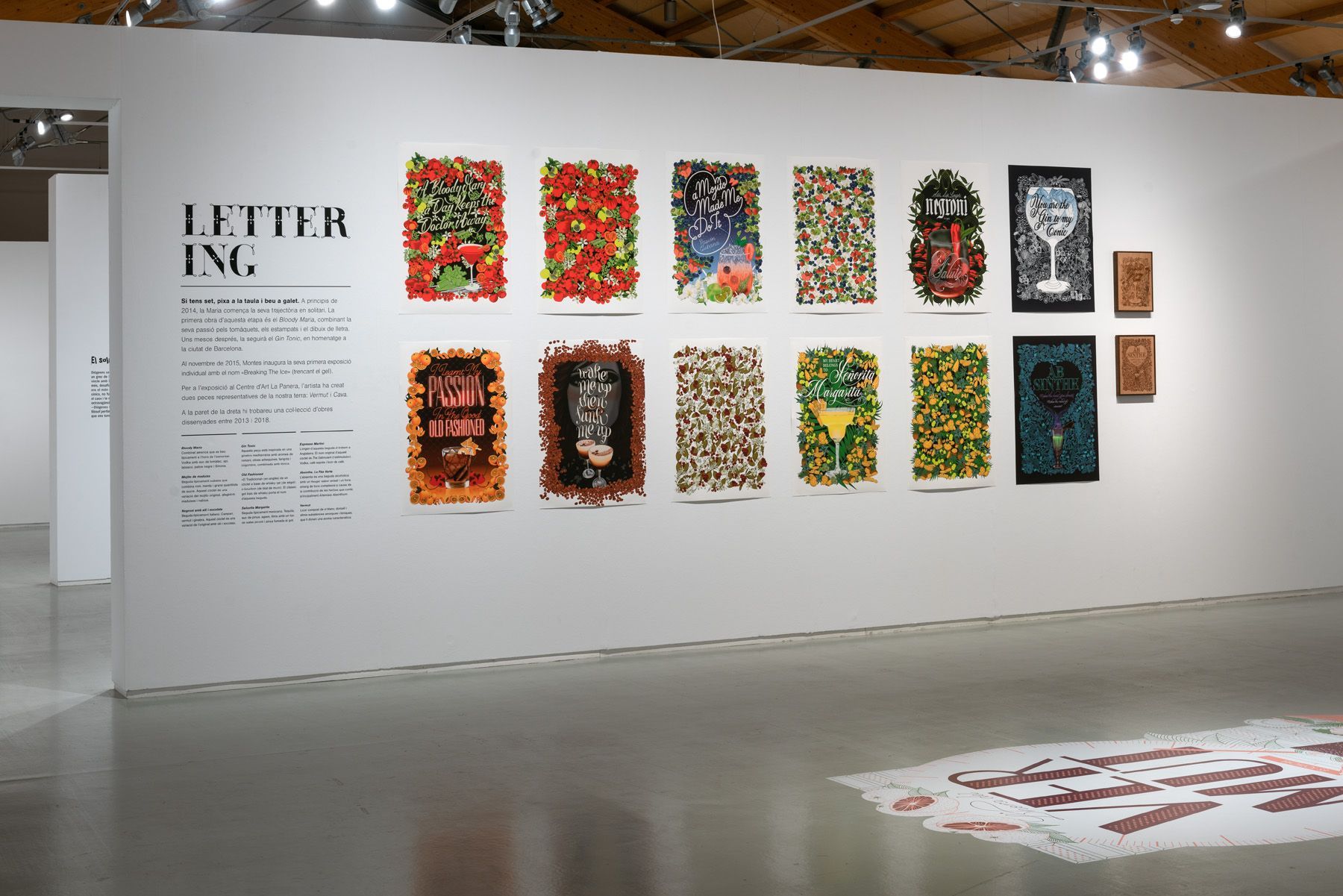 Maria Montes standing beside colorful framed artwork displayed on a white gallery wall