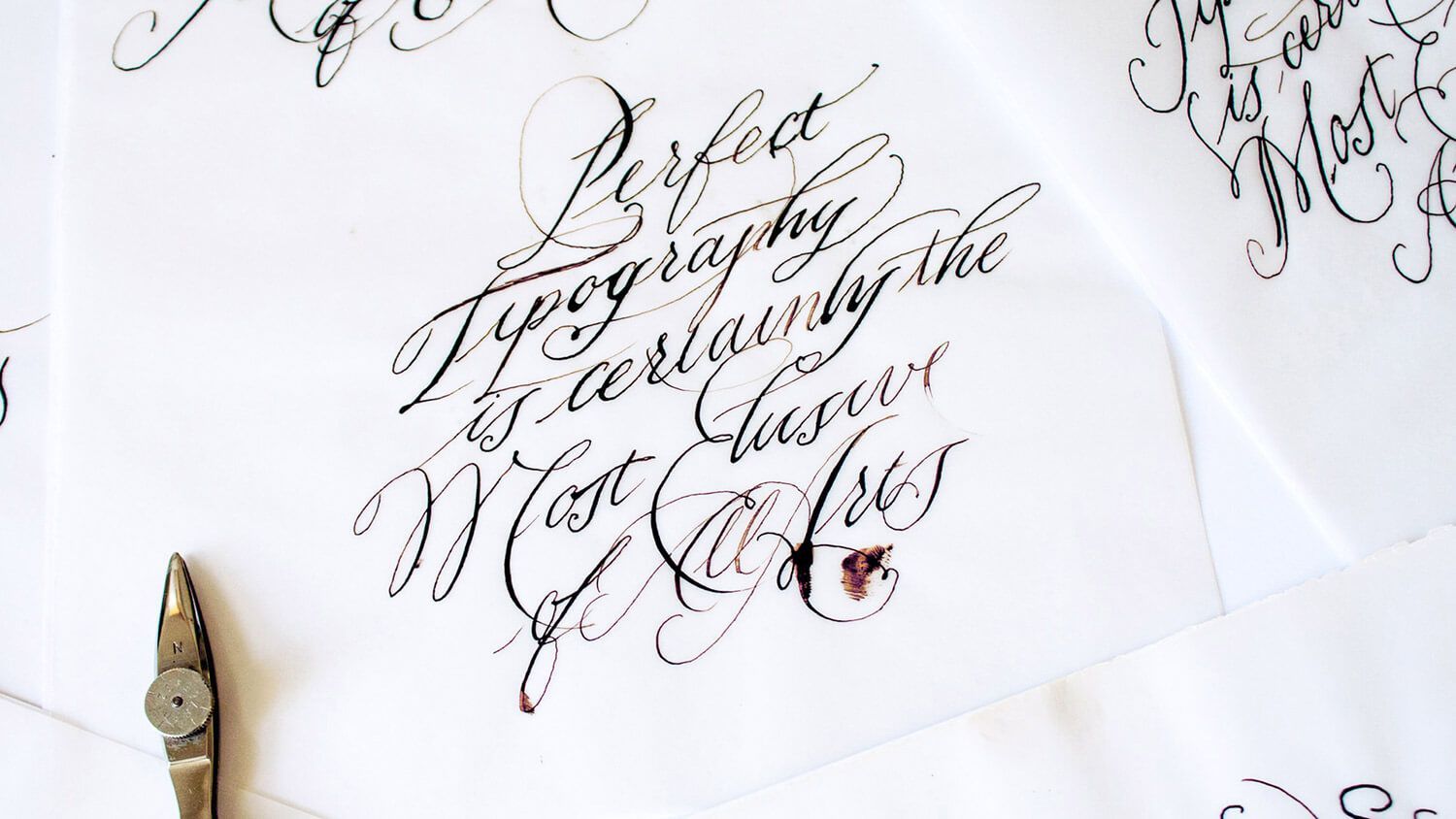 Elegant black calligraphy on white paper with a gold pen nib visible at the lower left