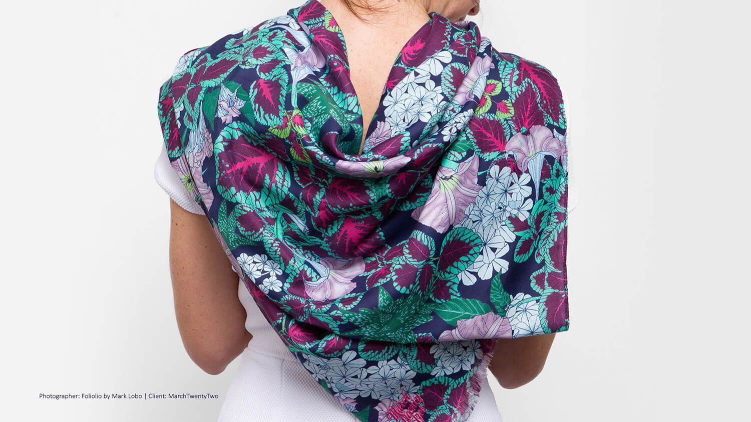 Woman wearing a colorful floral scarf draped over her shoulders against a white background