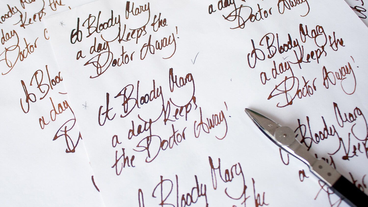 Handwriting practice on white paper with brown calligraphy and a pen at the right edge