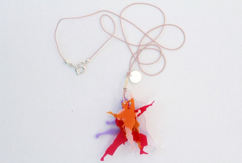 Pendant necklace with a clear bead and orange-red abstract dangling charm on a white background
