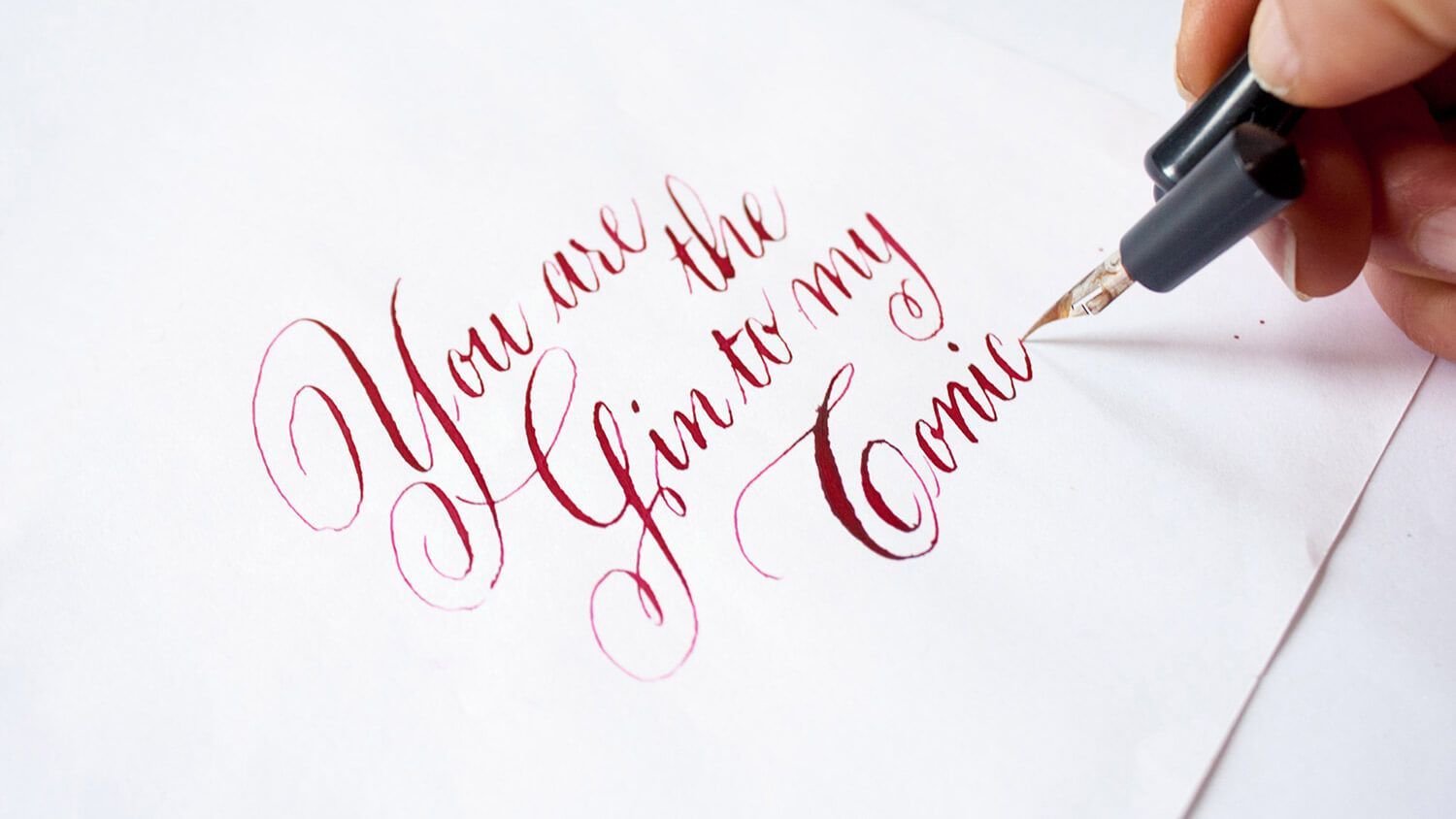 Hand writing “You are the Greatest Comeback” in elegant red calligraphy on white paper