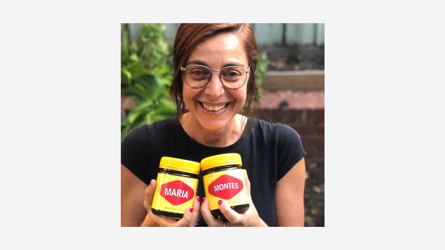 Maria Montes smiling and holding two yellow-and-pink condiment jars outdoors