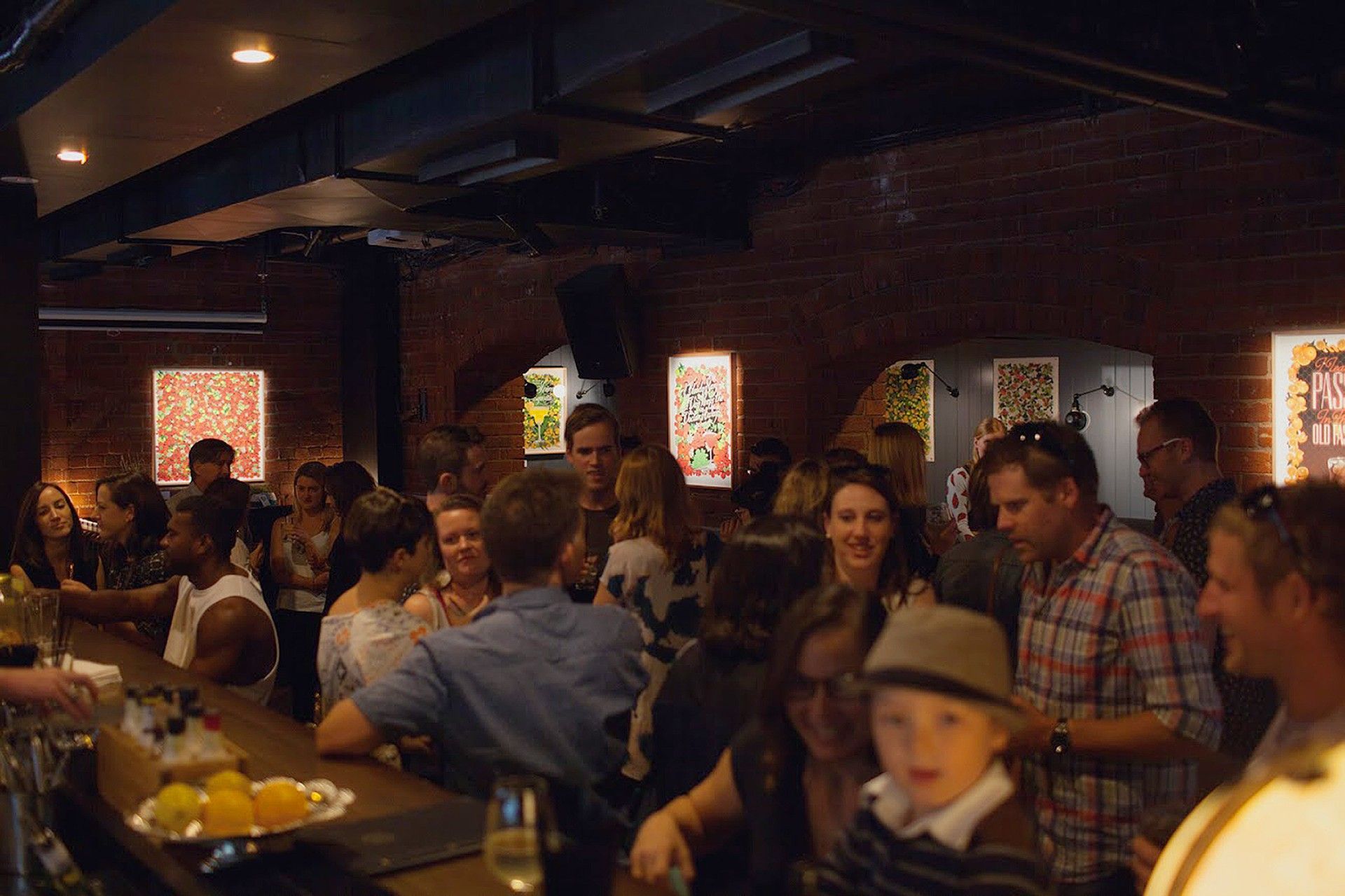 Crowded bar with people chatting at tables under warm dim lighting