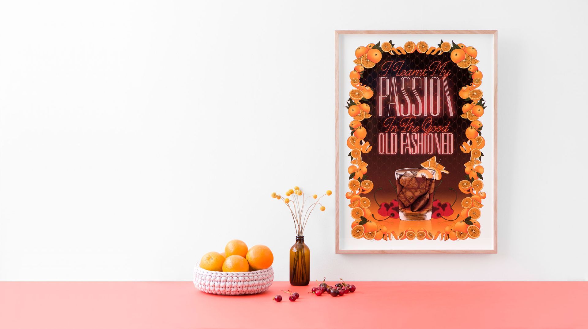 Framed autumn wreath poster on a pink table with oranges, berries, and a vase of dried flowers