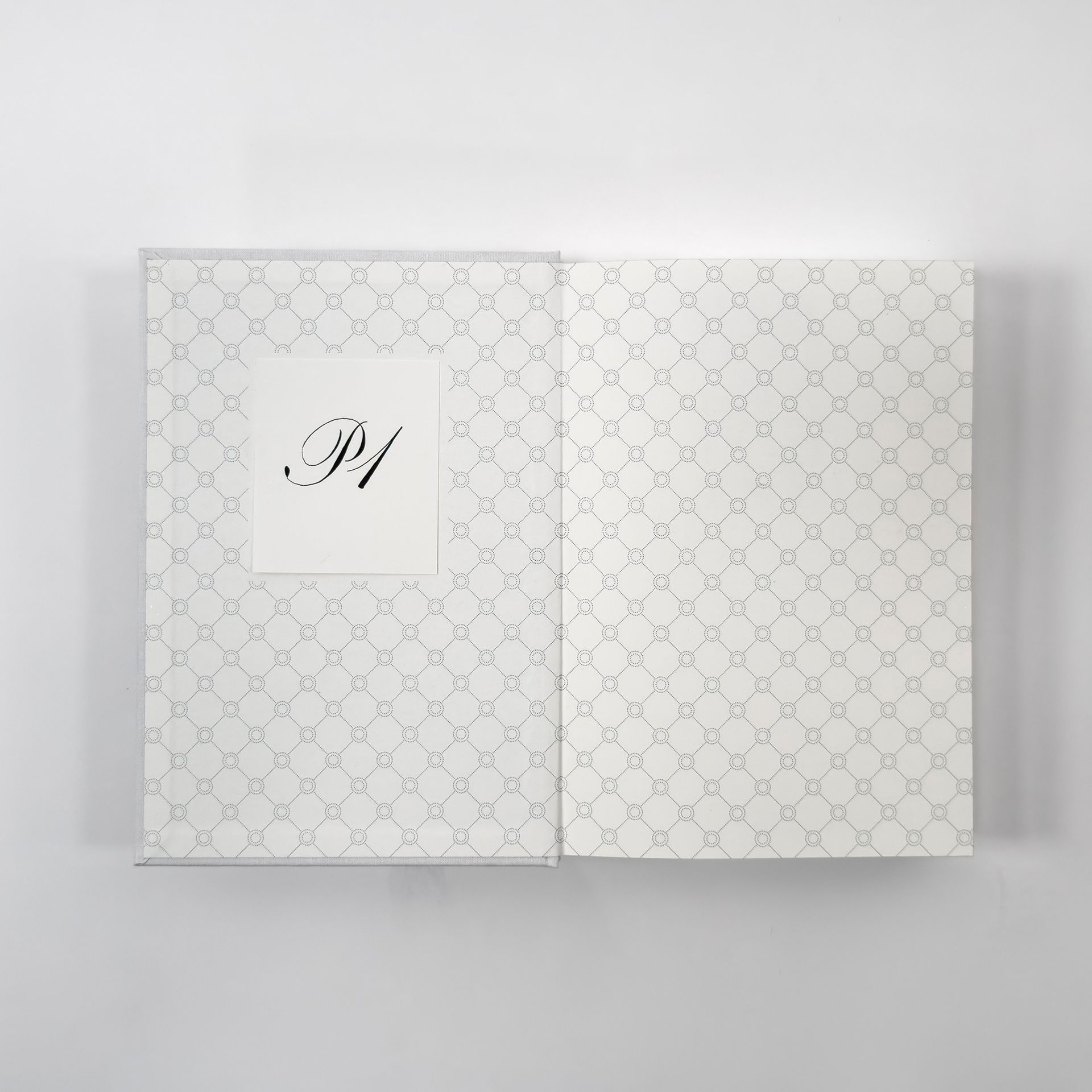 White patterned stationery box with a centered monogram label on a light gray background