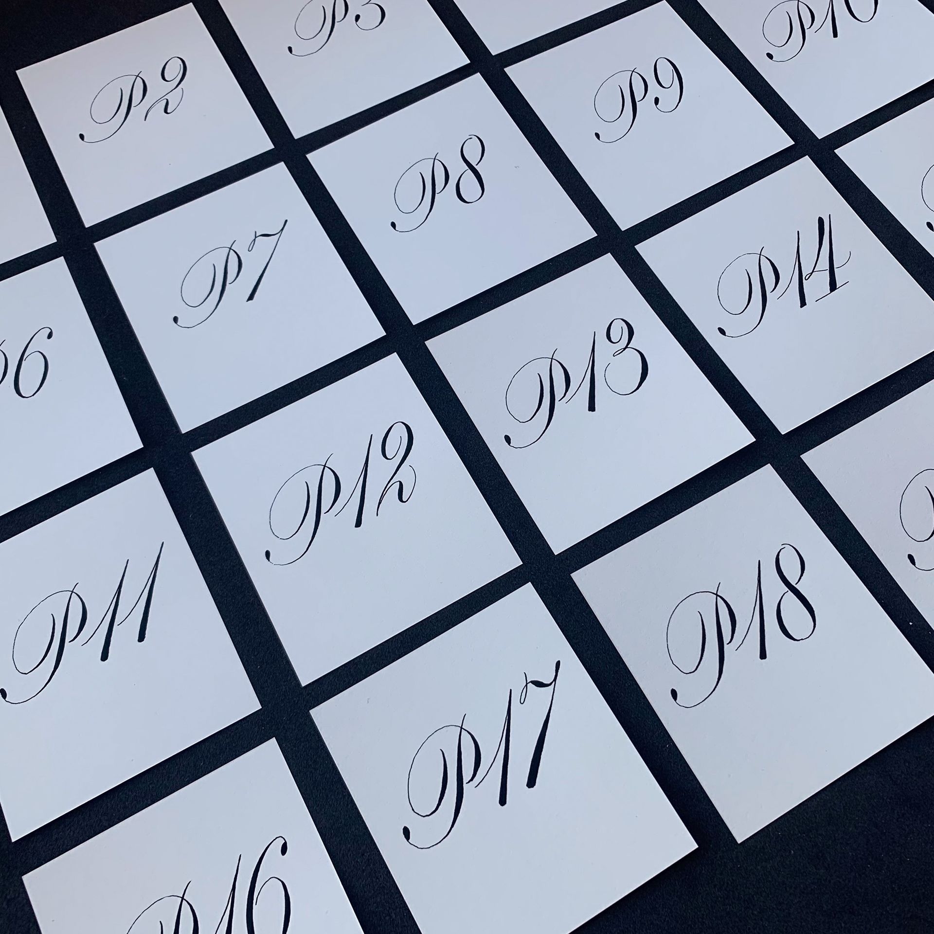 Diagonal grid of numbered white tiles with elegant cursive letters, viewed close up