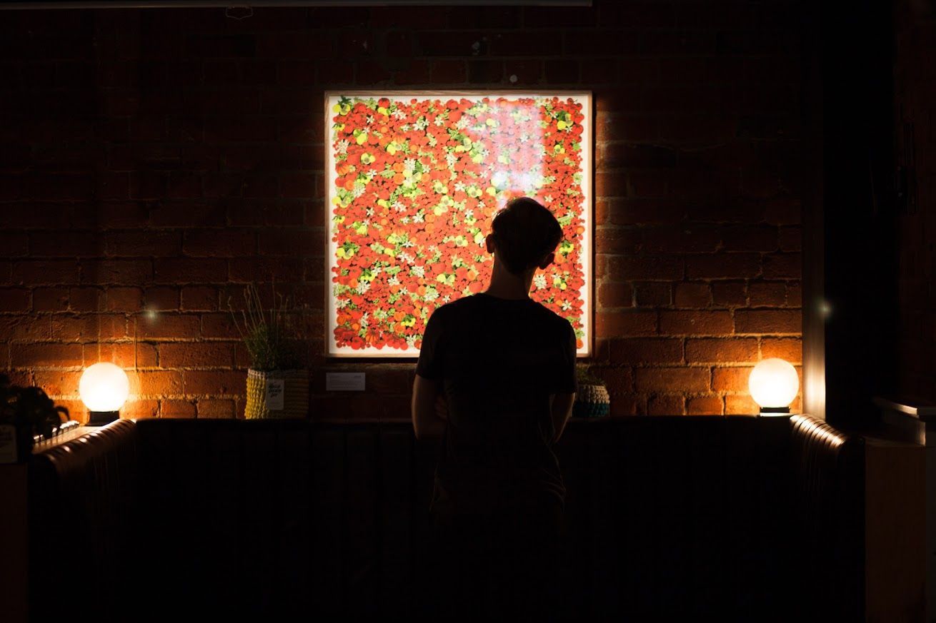 Silhouette of a person facing a bright, colorful screen in a dimly lit room with lamps on both sides