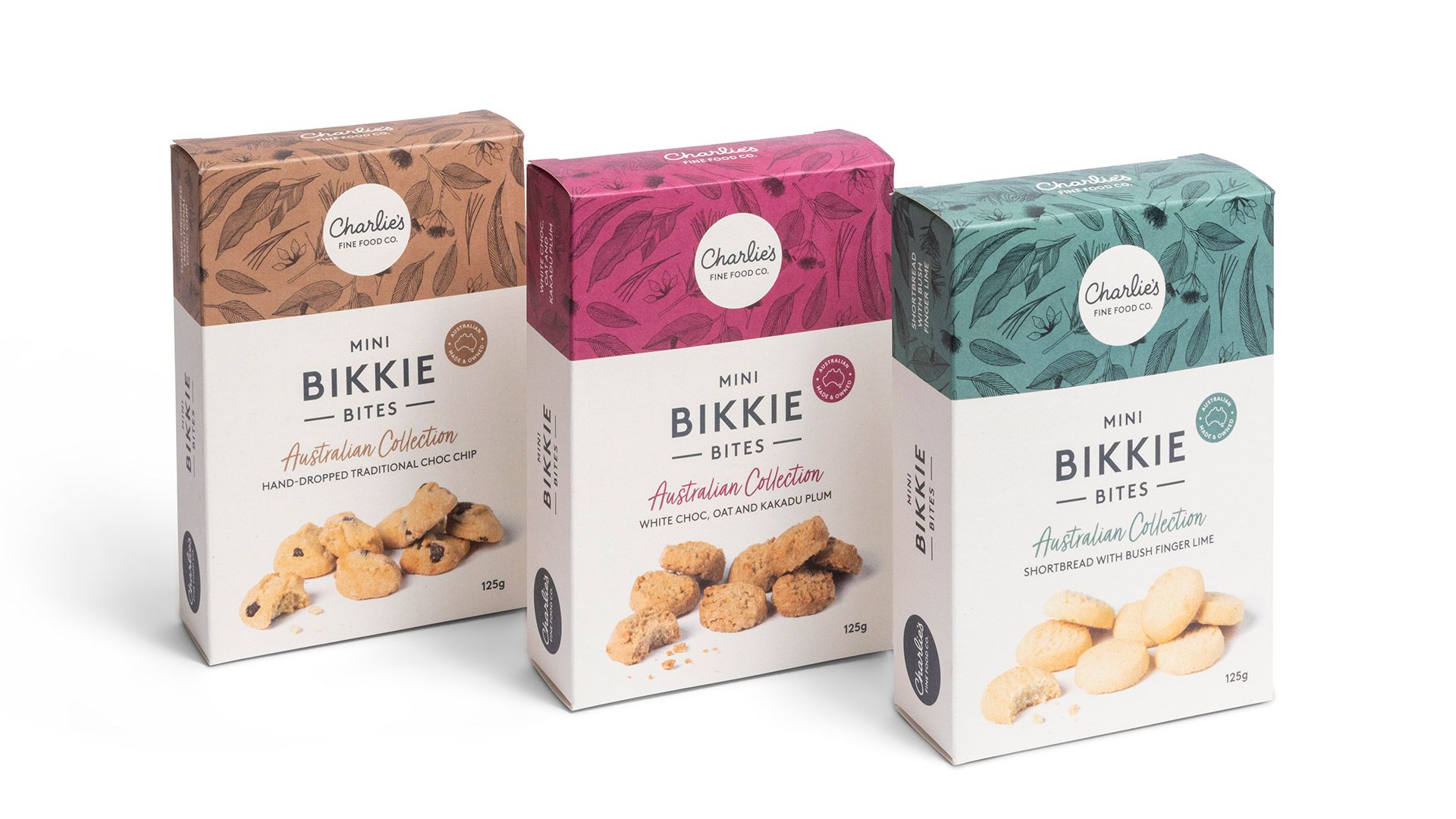 Three Bikkie cookie boxes in cream, pink, and teal packaging with wooden tops.