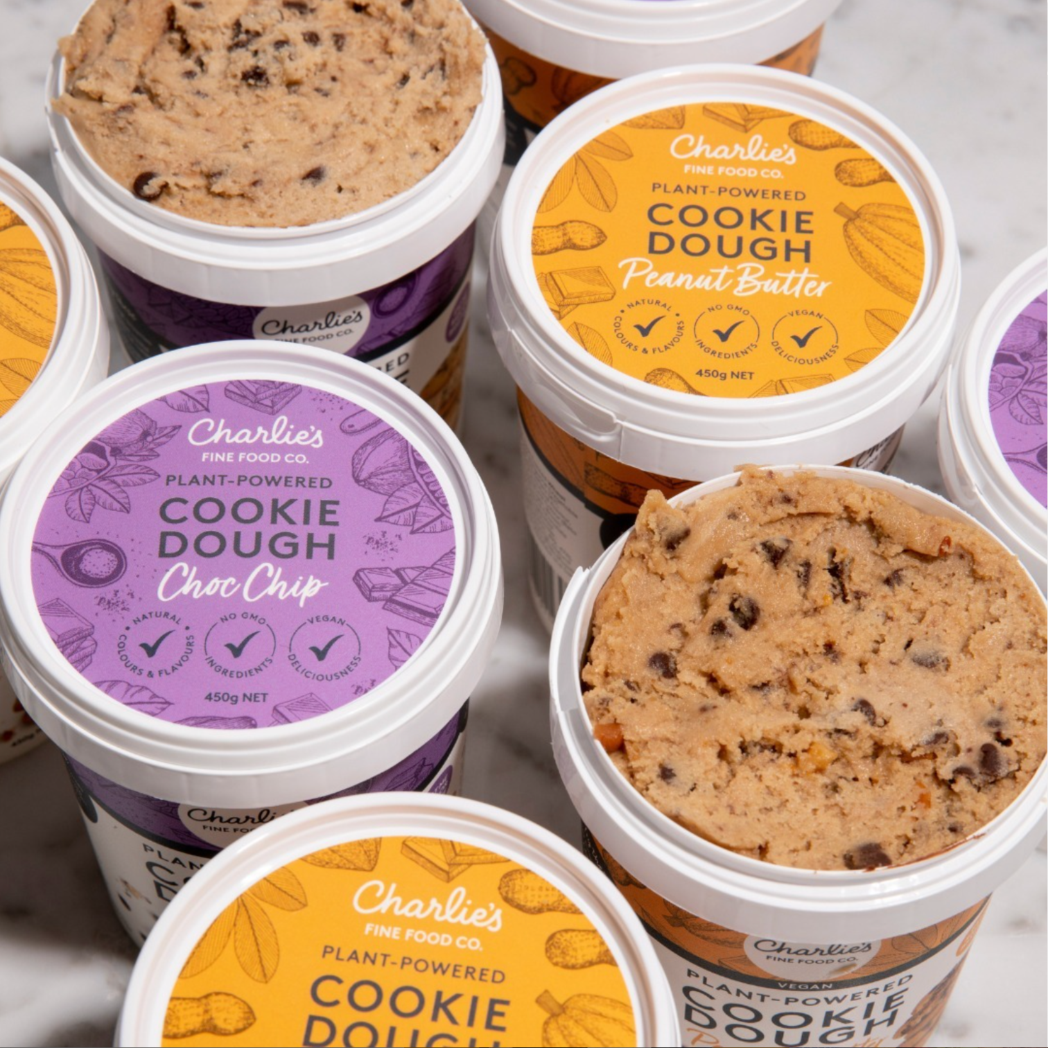 Assorted Charlie's frozen cookie dough pints in purple, orange, and white lids stacked together