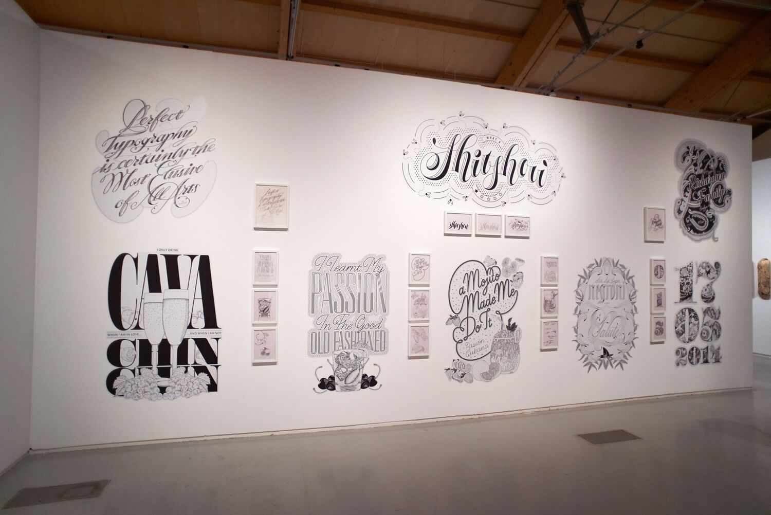 Art gallery wall with large black-and-white typography and calligraphy prints displayed in a row