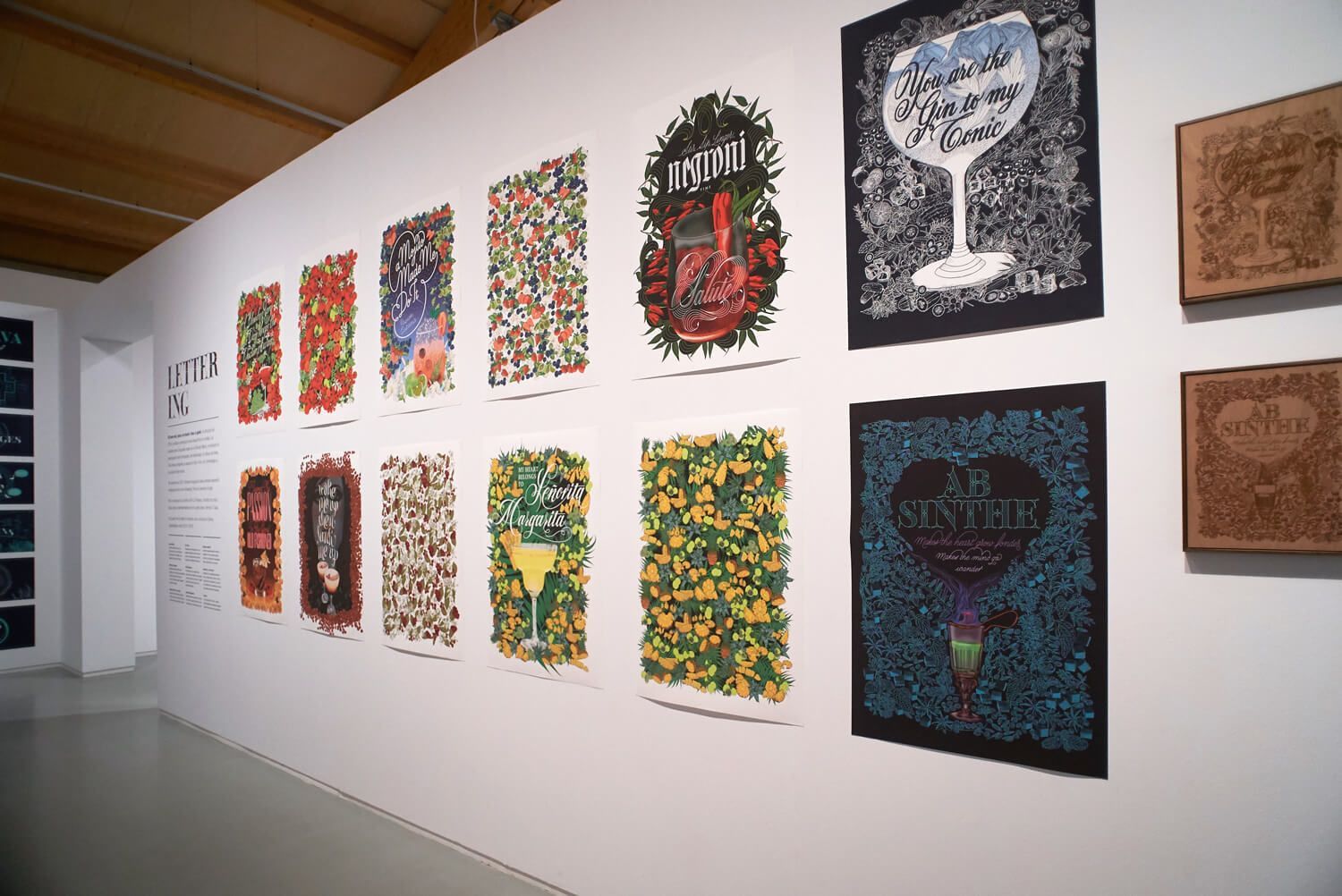 Gallery wall of colorful mixed-media artworks, including two large pieces on a white wall.