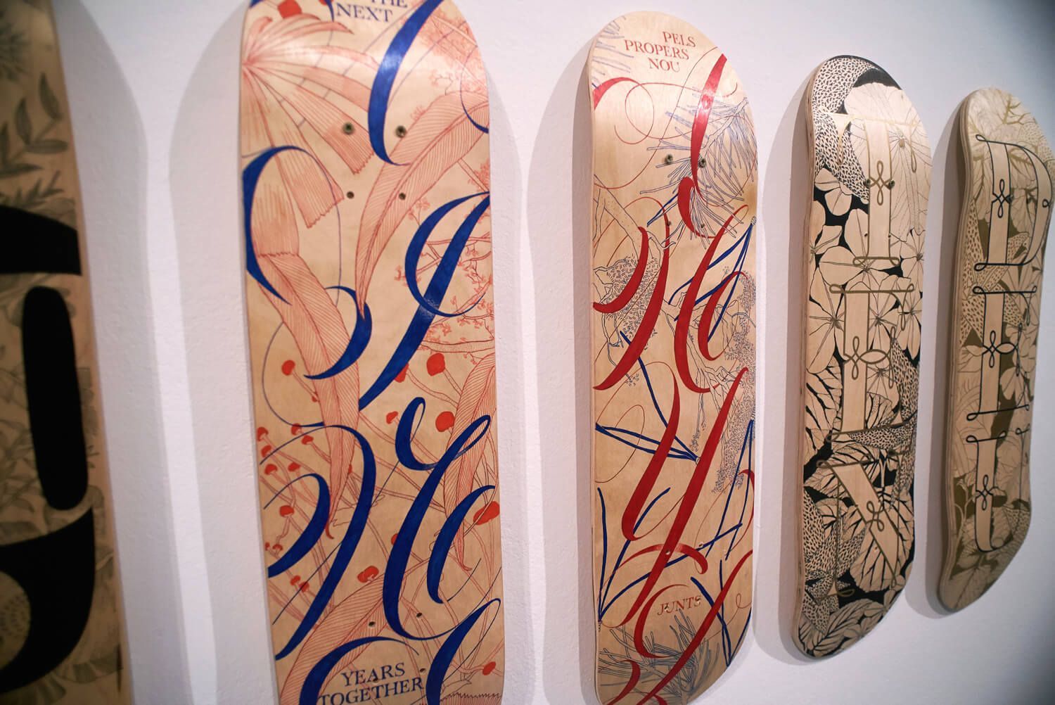 Skateboard decks with abstract blue, red, and black designs displayed on a wall