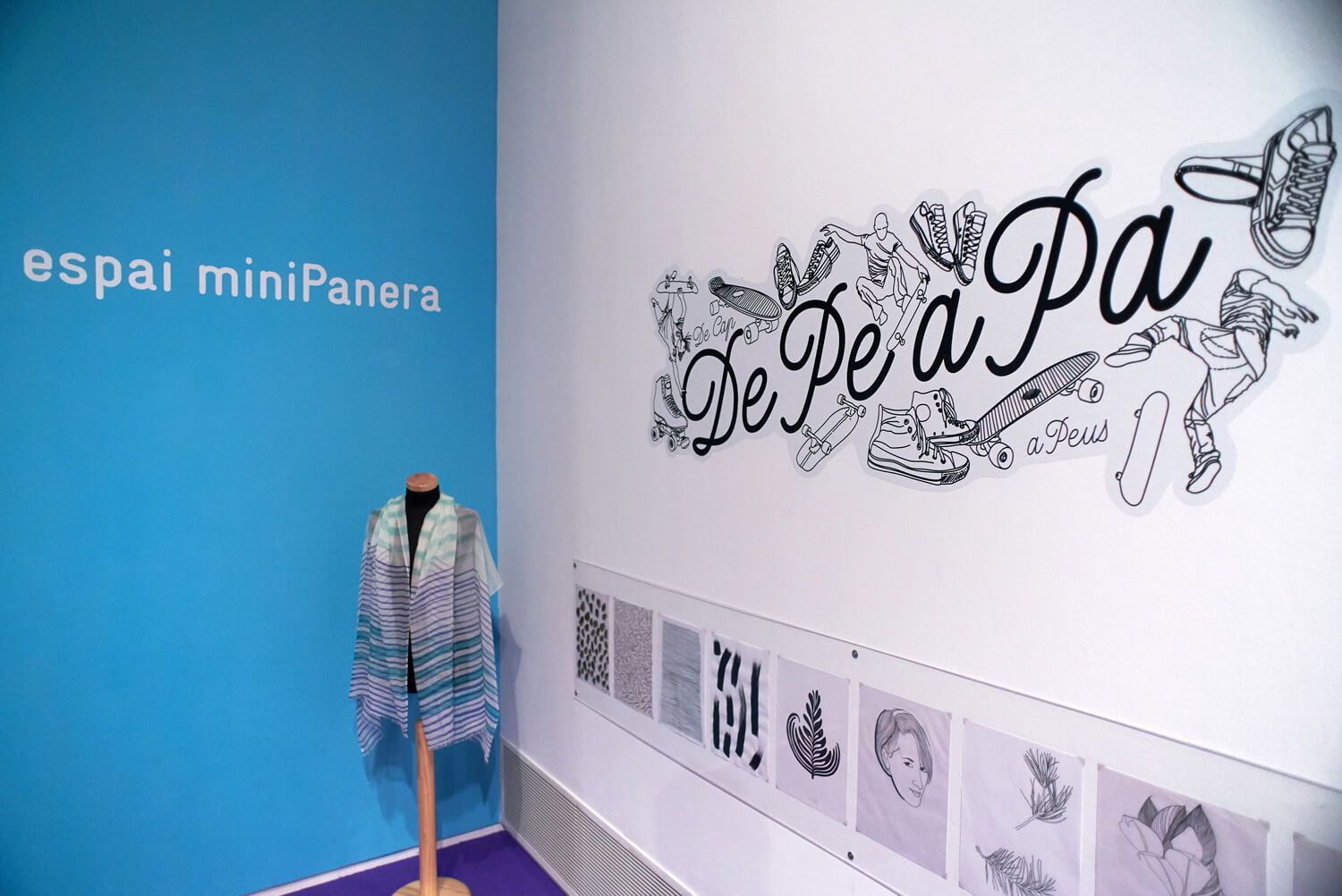 MiniPanera gallery wall with blue accent wall, mural text, and a striped garment on a stand