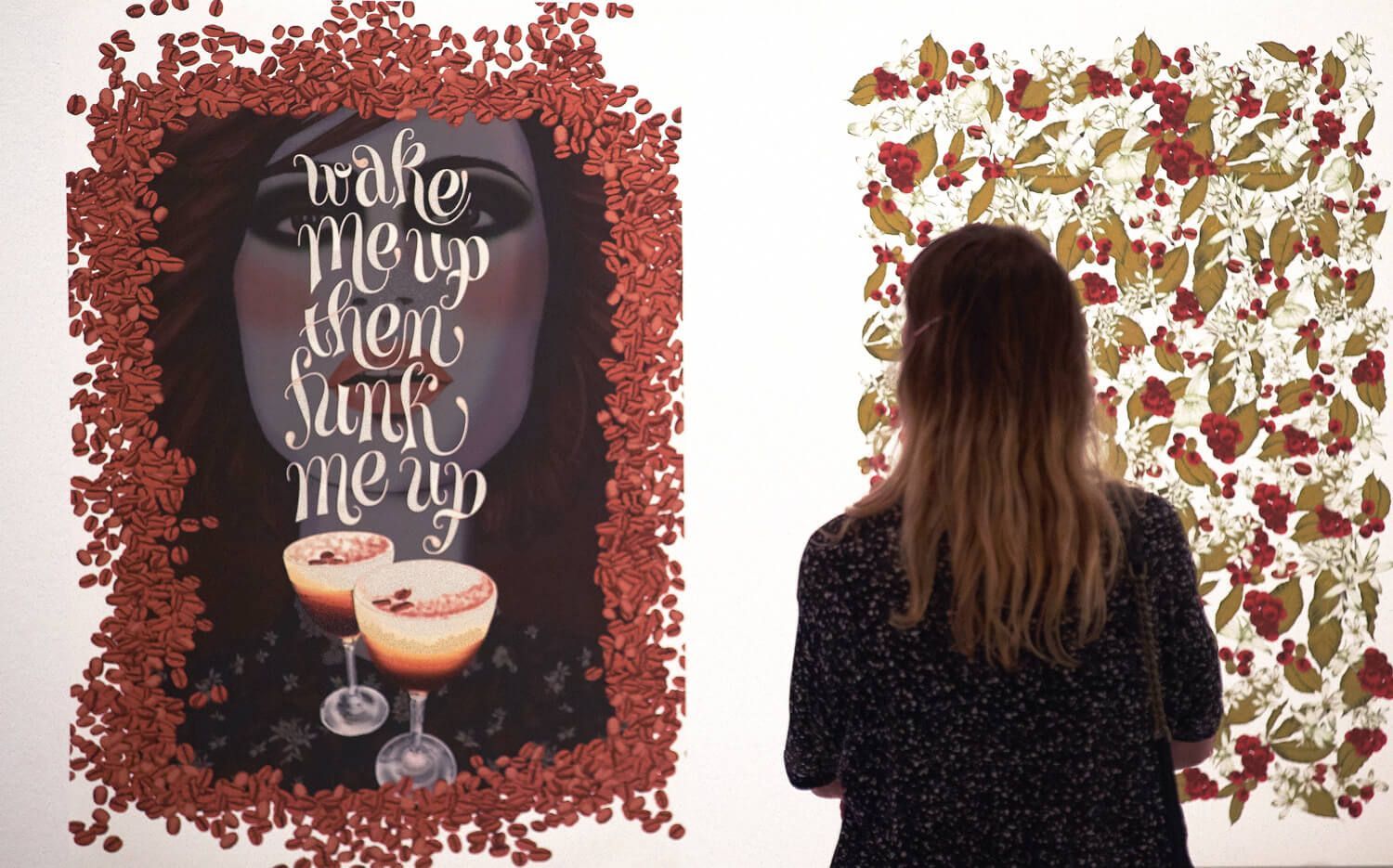 Woman studies an art wall with a red floral heart and a butterfly collage in a gallery