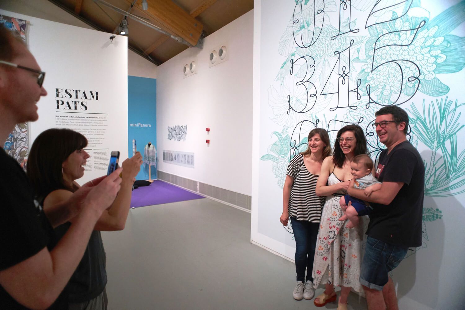People posing for a photo in an art gallery beside a large wall mural