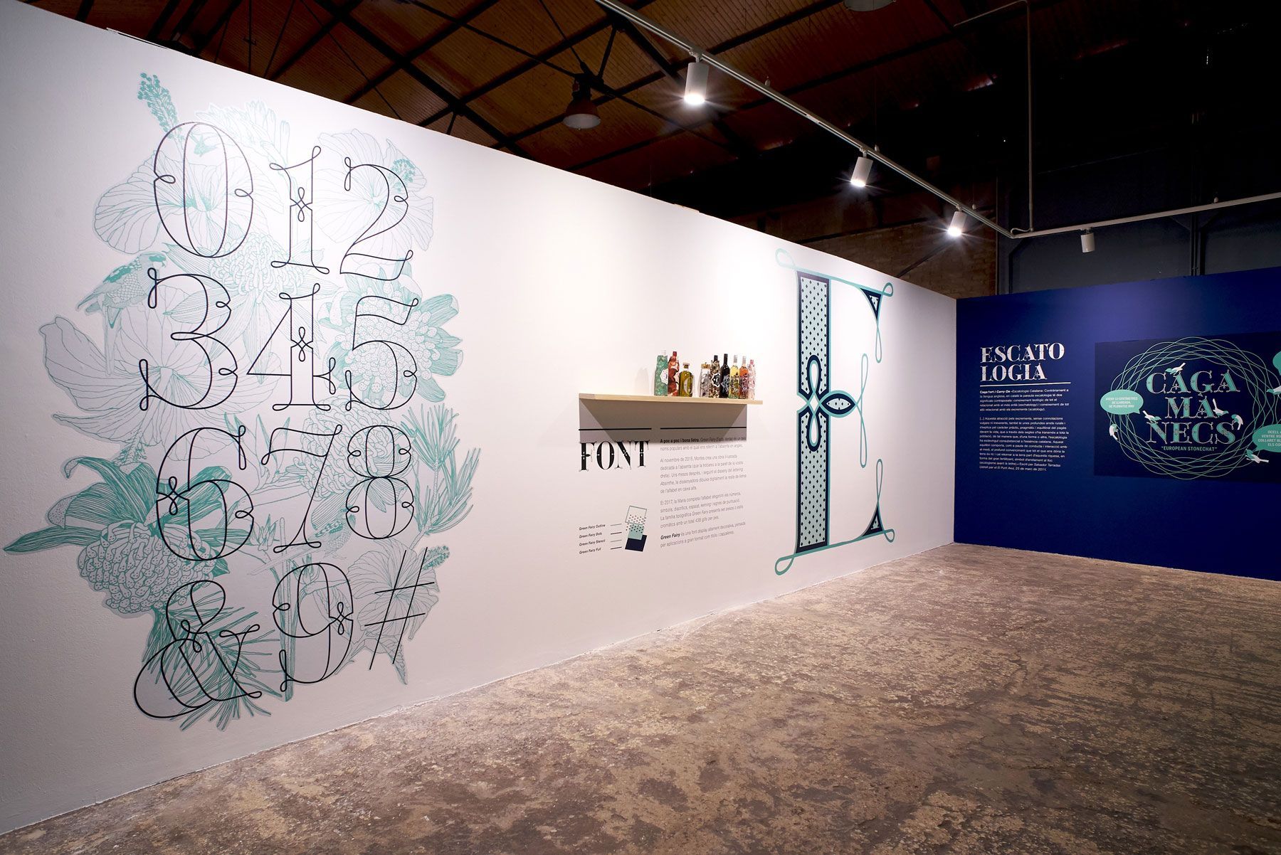 Gallery exhibition with white walls, blue mural, and large hand-drawn illustrations under spotlights.