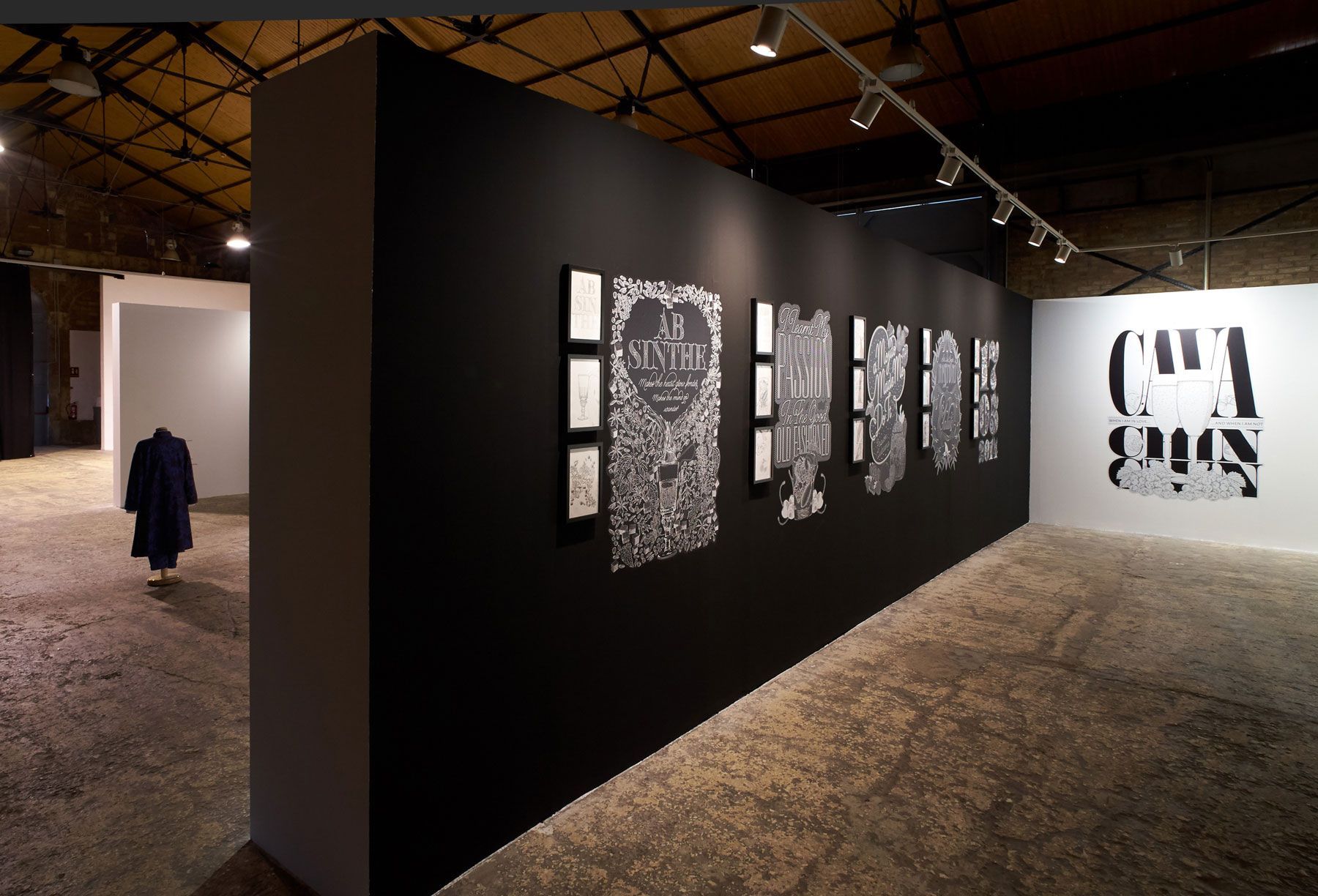 Art gallery with black wall-mounted abstract artworks under gallery lighting