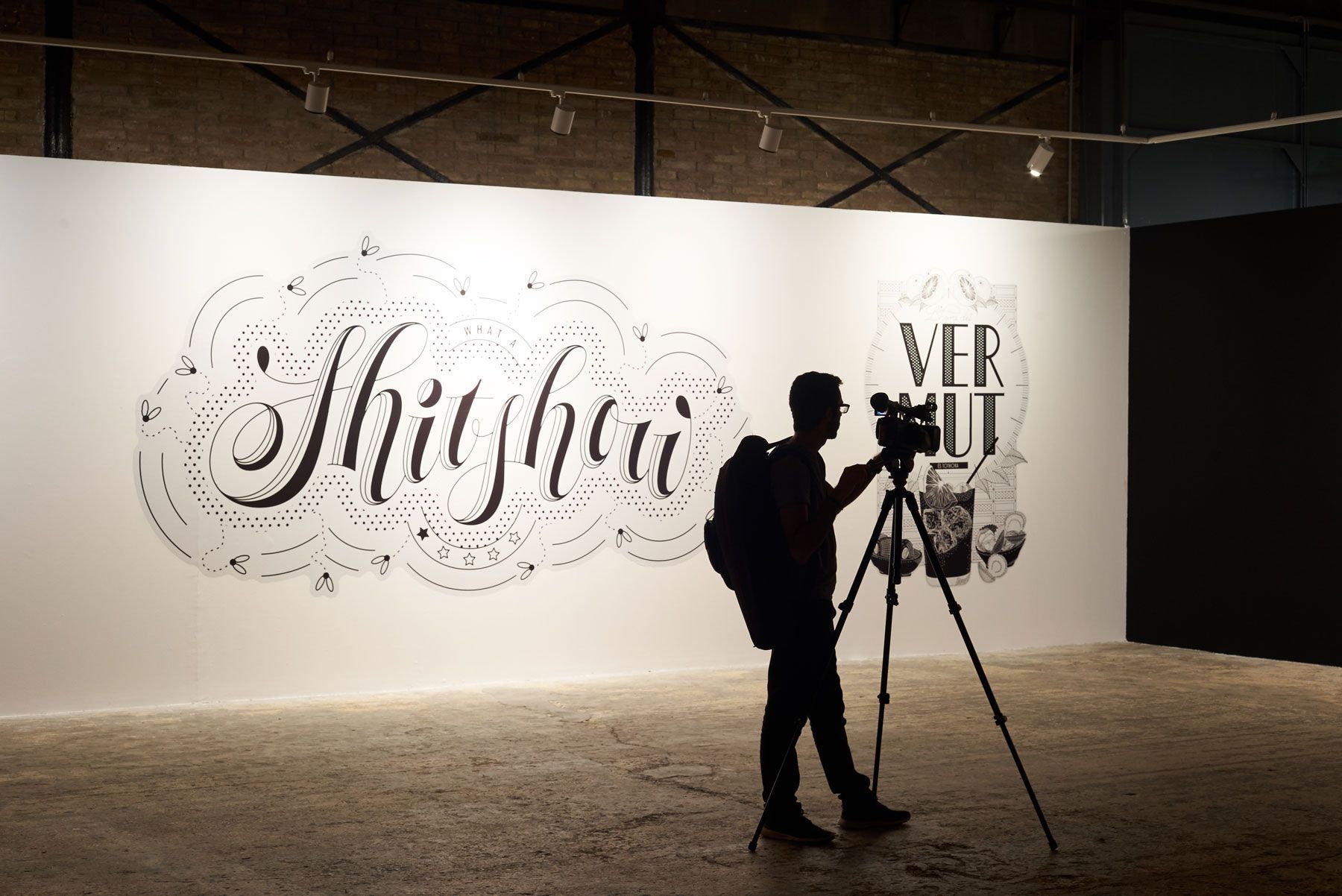 Silhouette of a photographer with tripod filming a large illuminated wall mural at night