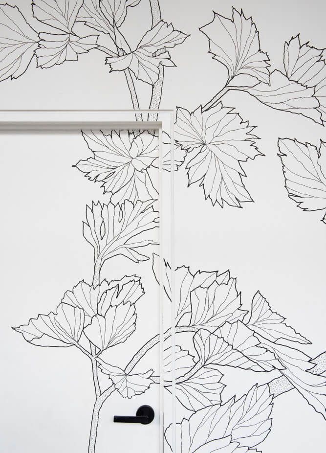 A black and white image shows a hand-drawn calligraphy sketch on grid paper with a pen resting on the side.