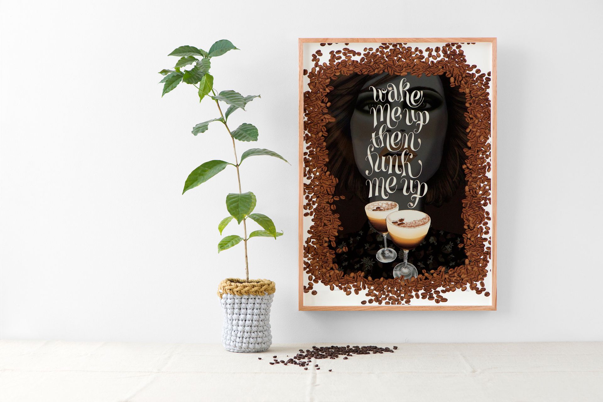 Potted plant beside framed coffee quote art on a white wall, with a cup and spill illustration