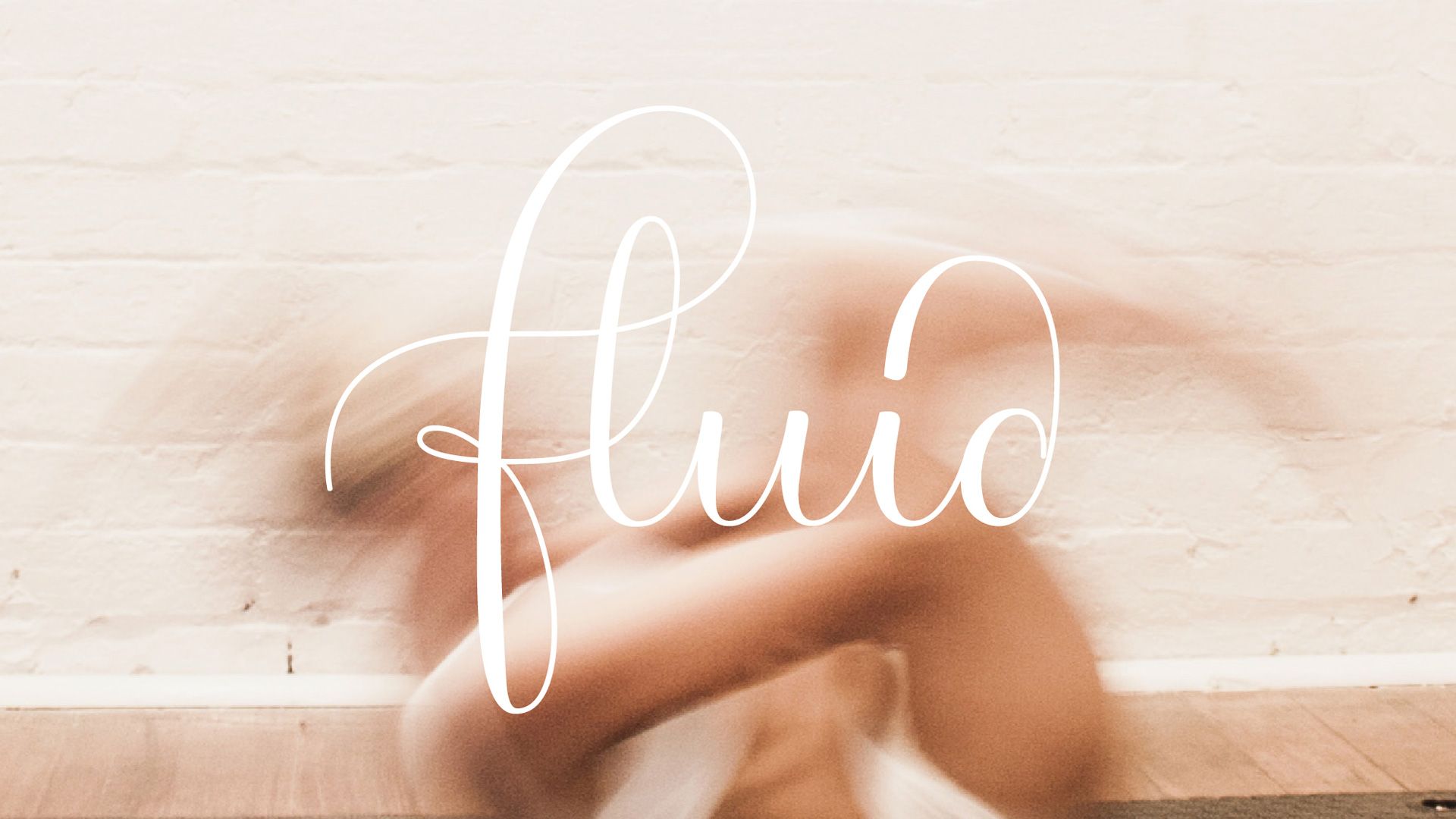 Soft-focus hands on a pale wood surface with the word “fluid” in white script overlaid.