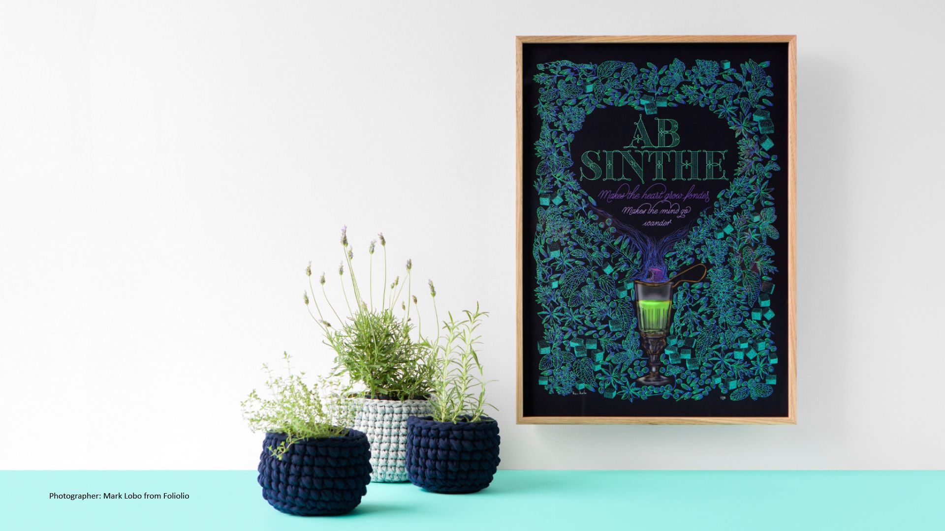 Framed colorful wall art above two potted plants on a white table against a white wall
