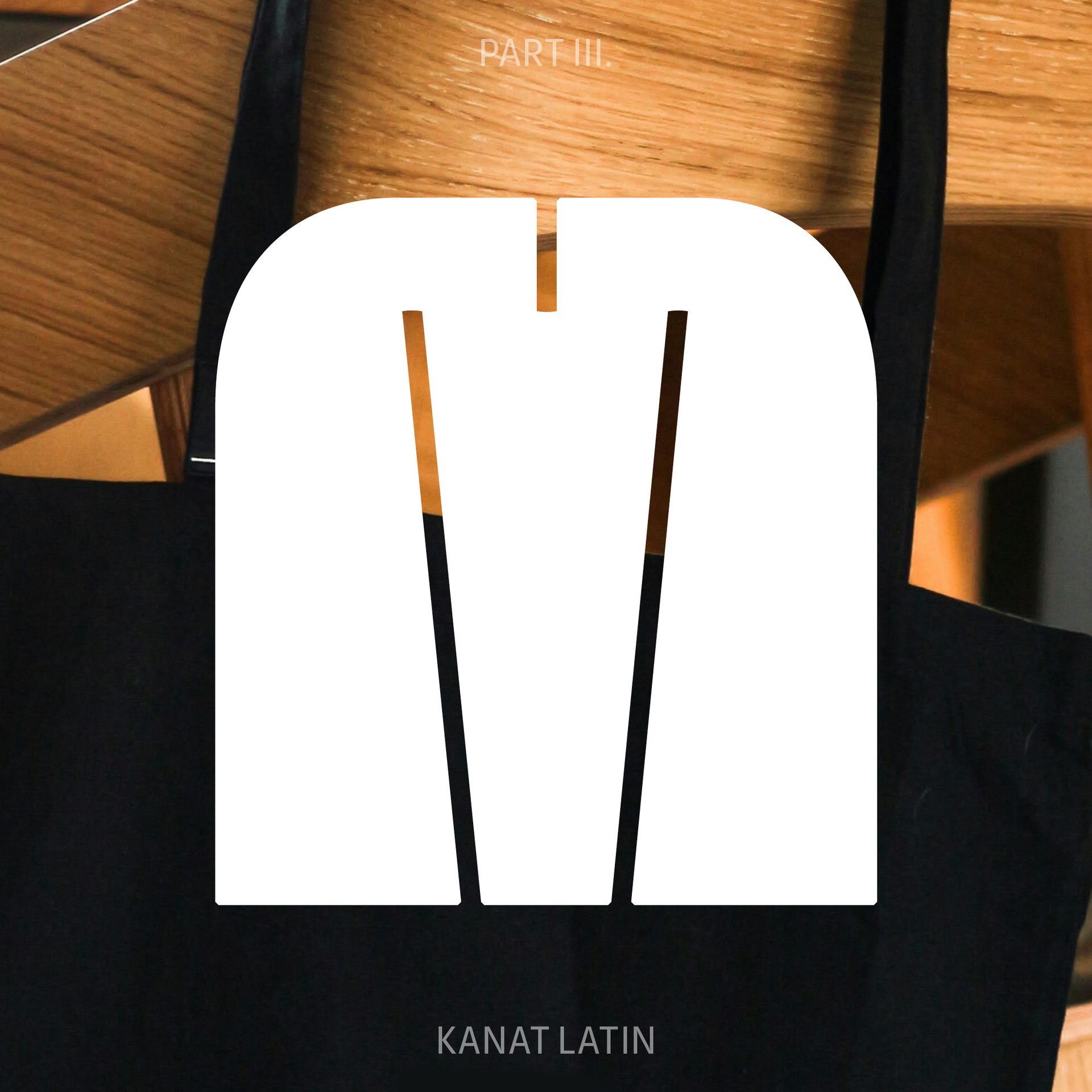 White monogram logo with a black split “M” over a blurred wooden background