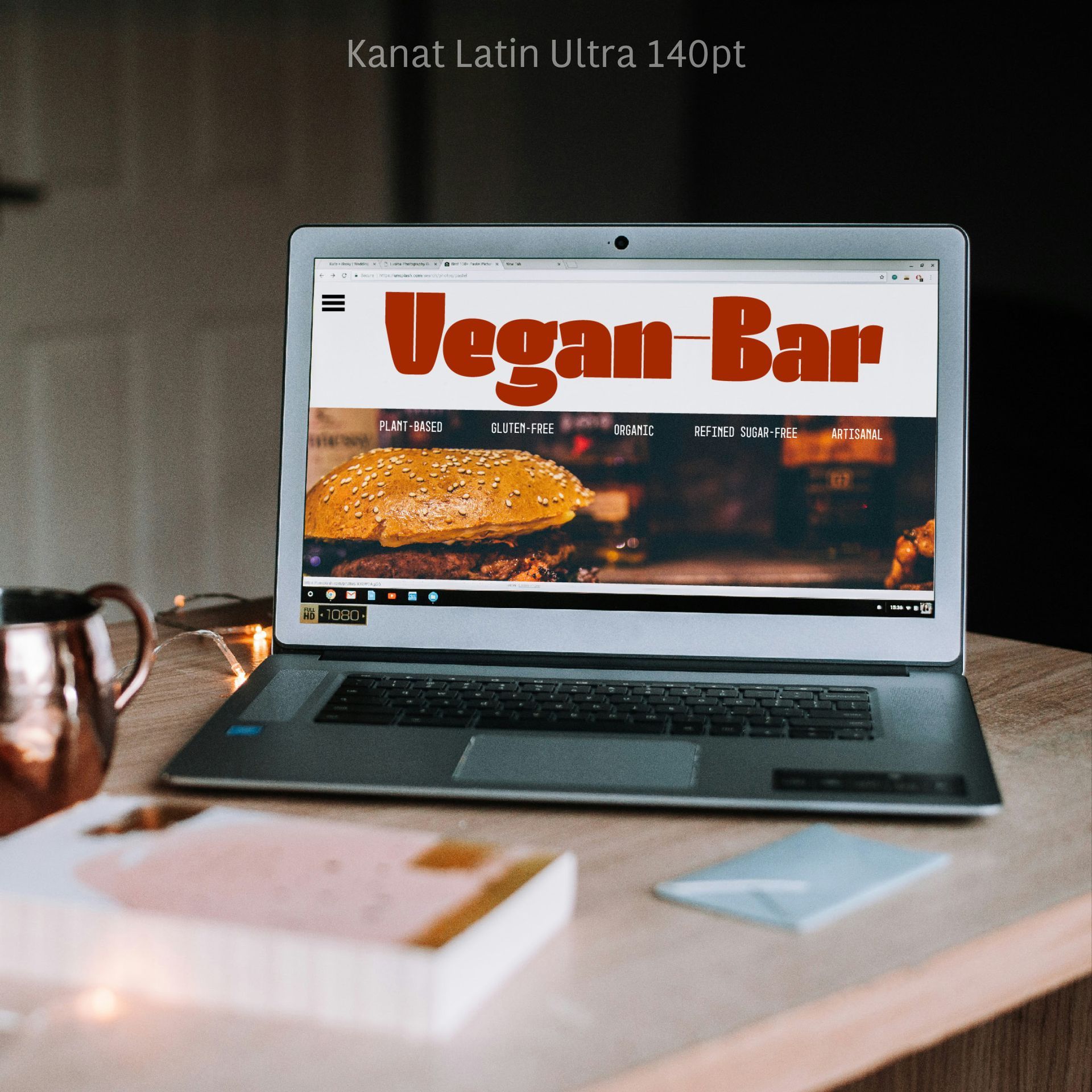 Laptop on a desk displaying a “Vegan Bar” website, with coffee and papers nearby.