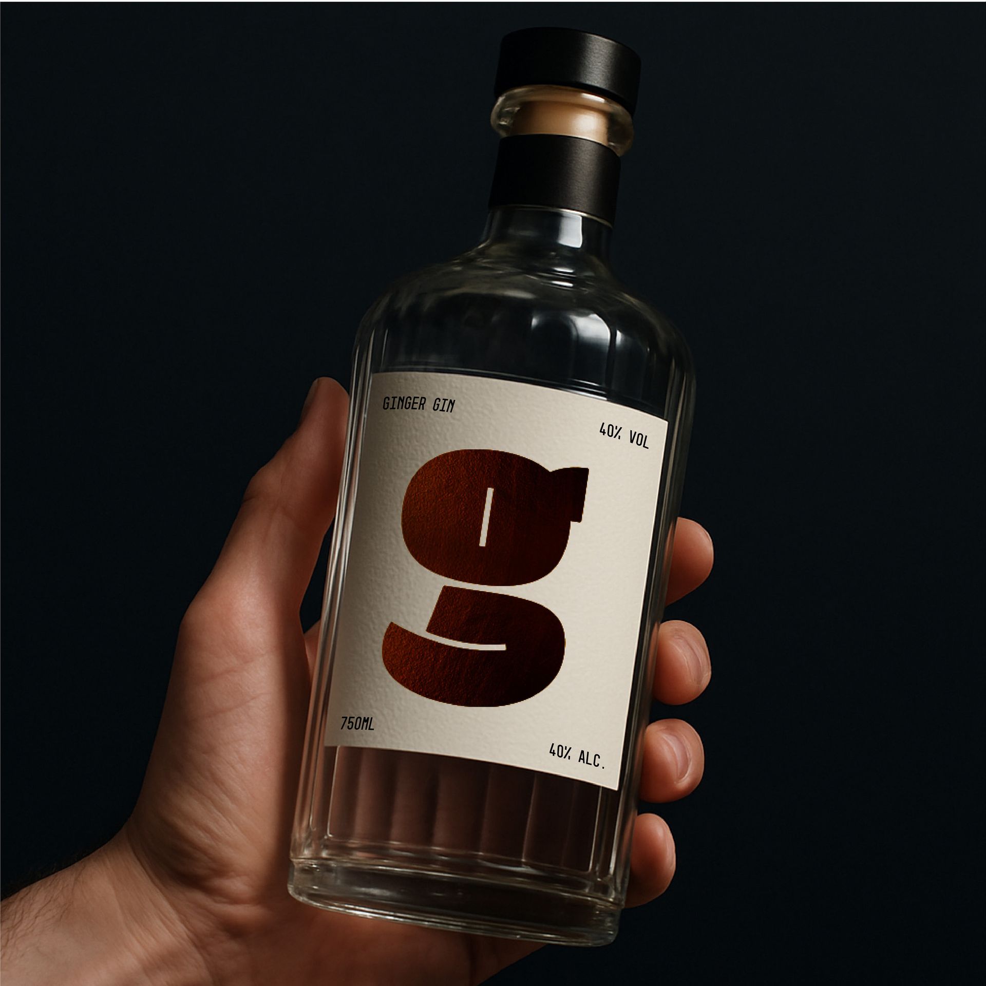 Hand holding a clear glass bottle with a white label and large dark red “g” on a dark background