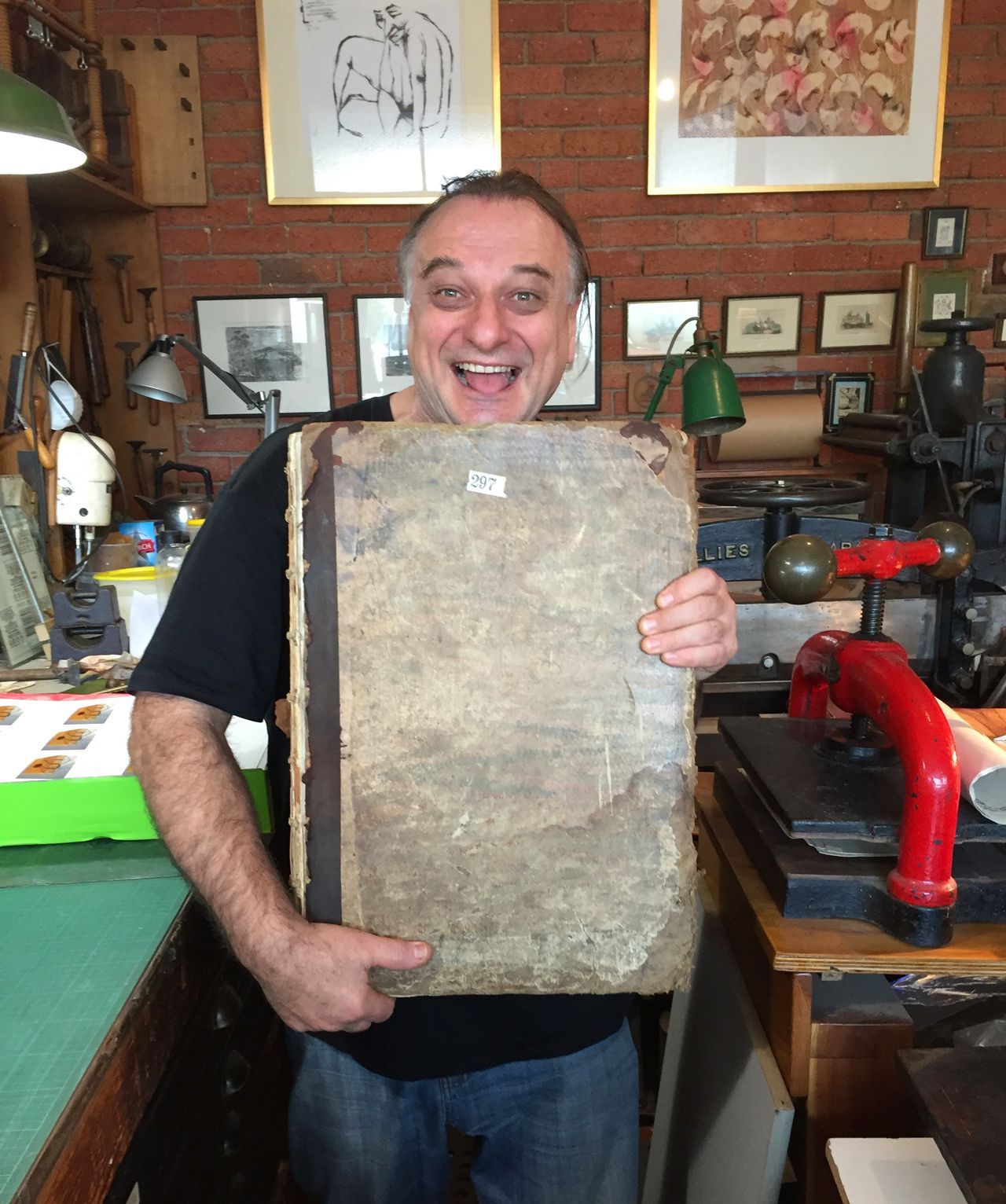 Nick Doslov smiling in a workshop, holding a large weathered stone slab