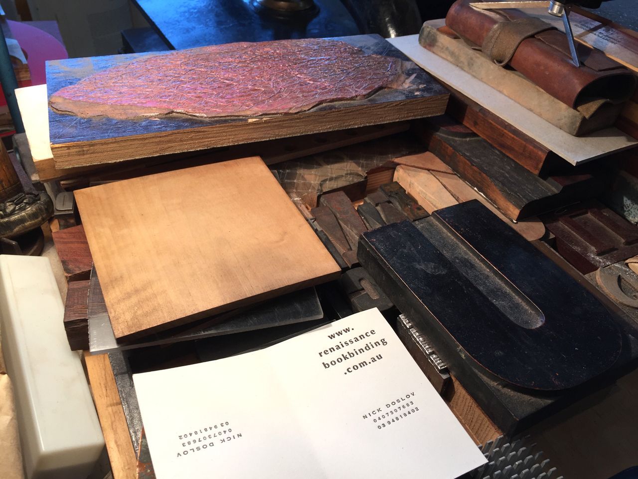 Stacks of assorted wooden blocks and sample boards on a workbench, including a white instruction sheet.