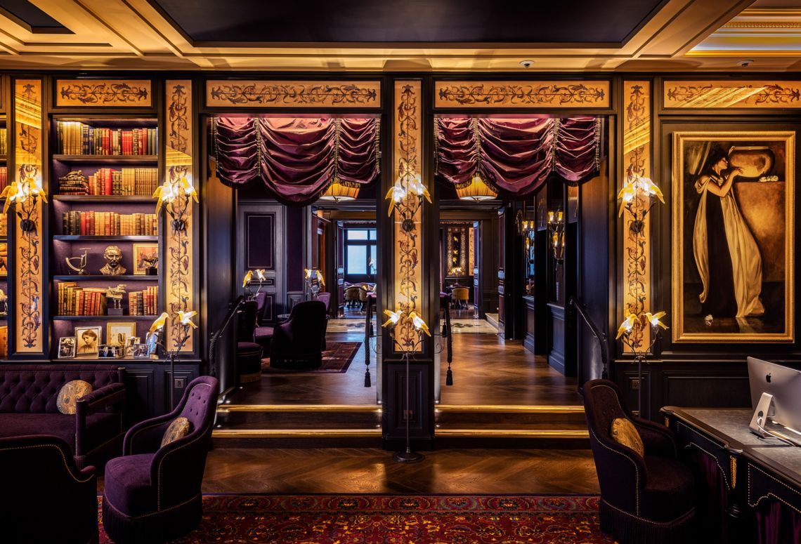 Elegant boutique interior with purple drapes, gold accents, and mirrored doors displaying designer clothing.